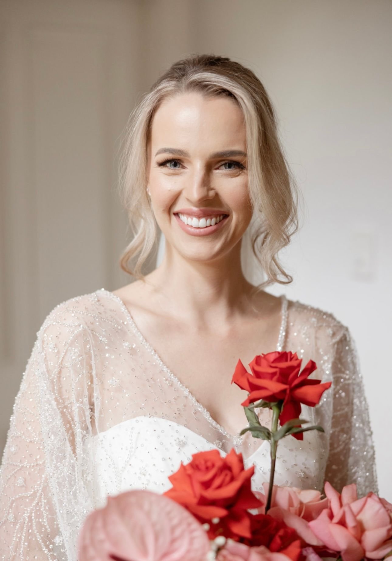 Smiling bride holding bouquet of red roses