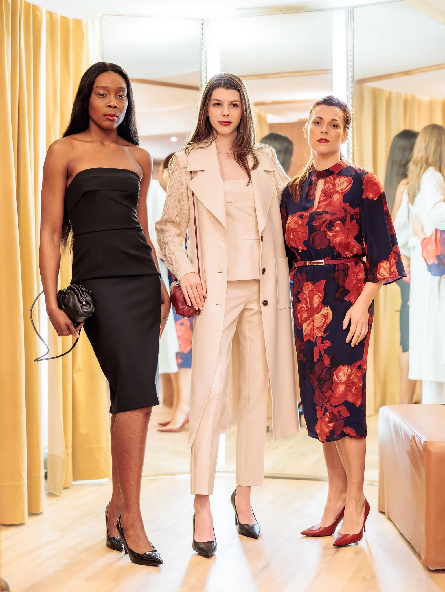 Trois femmes posant dans une boutique de vêtements, portant des tenues élégantes.