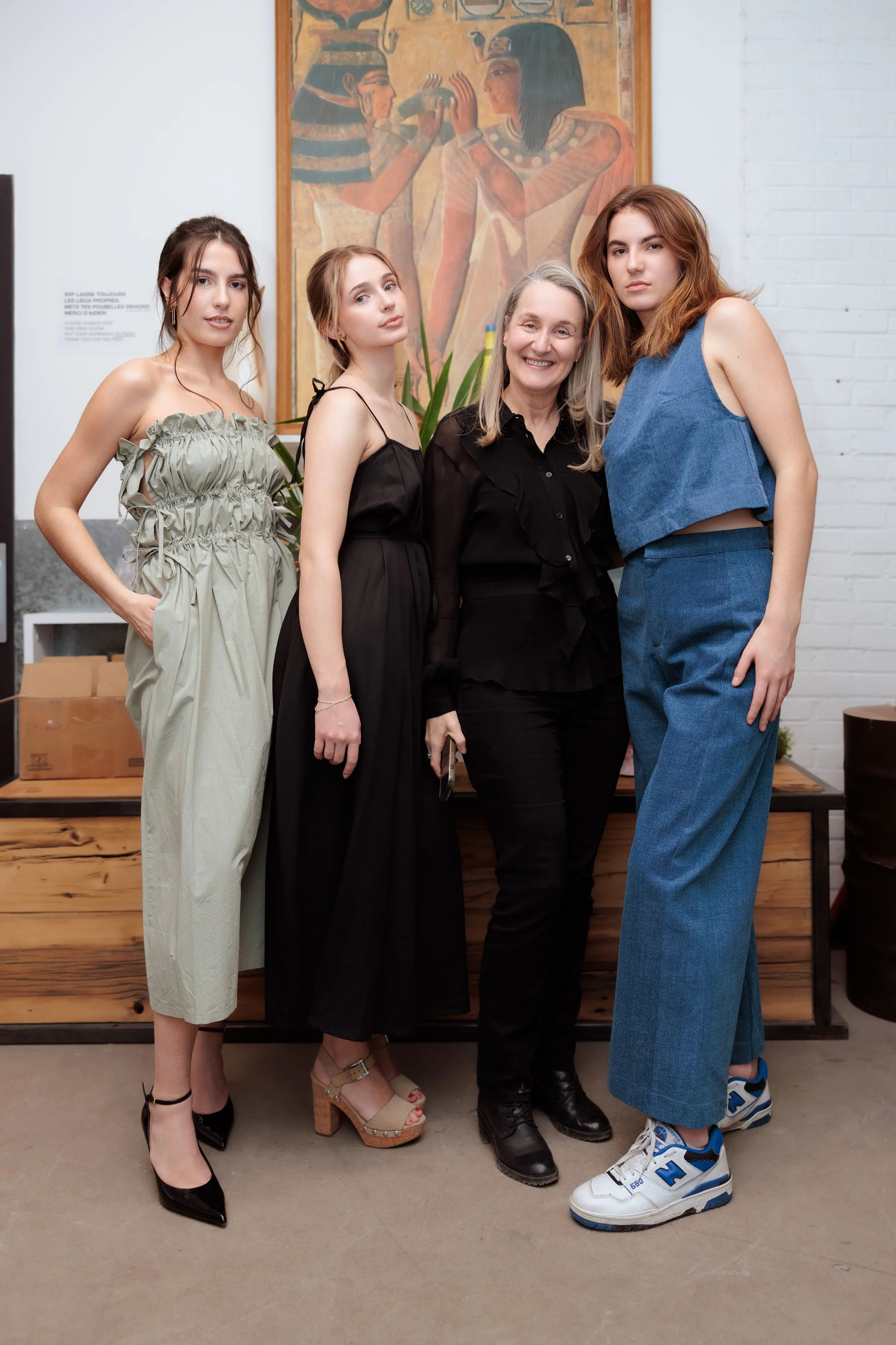 Quatre femmes posent devant un tableau égyptien dans une galerie d'art