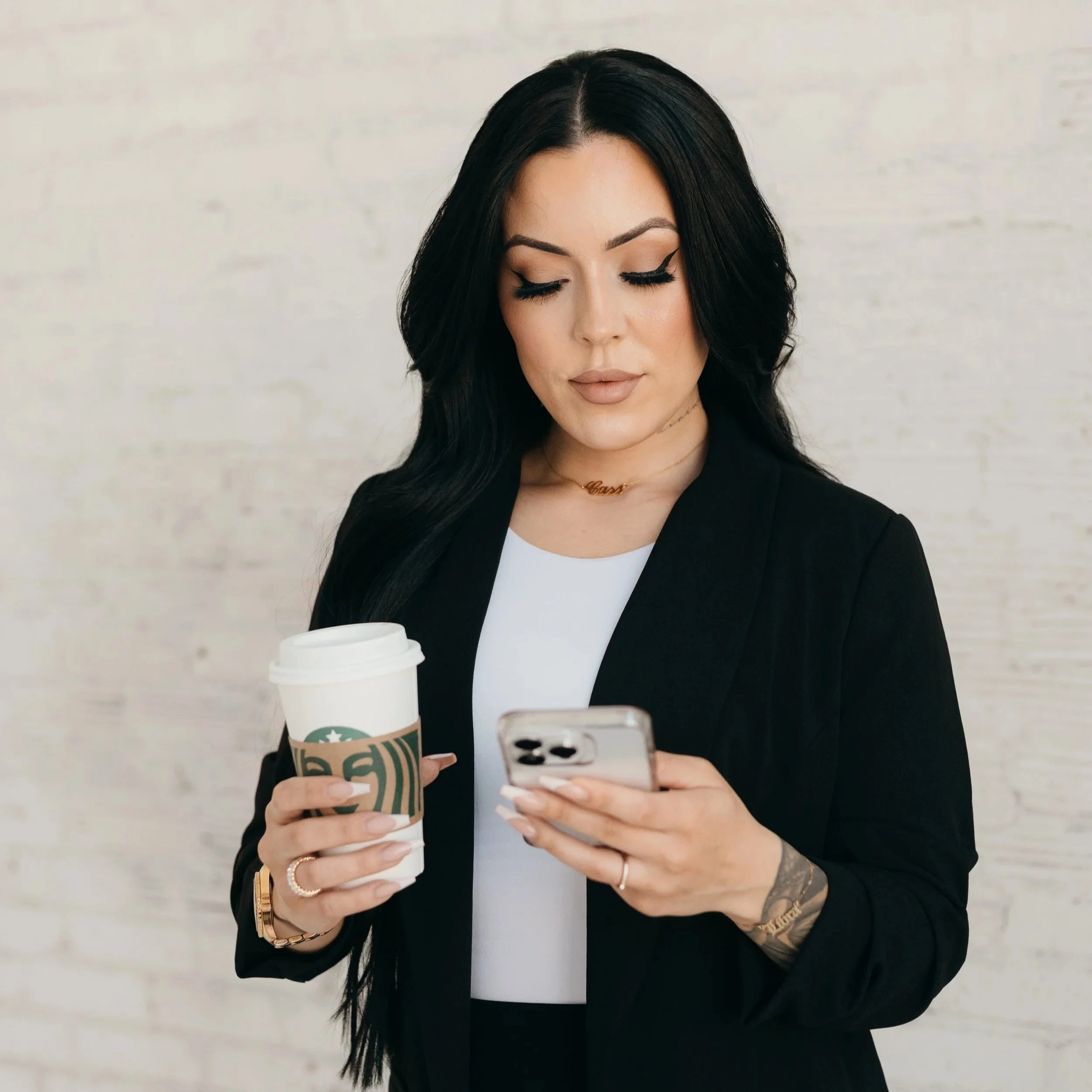 A close-up of a woman's waist showing a pocket containing a makeup brush, a small bouquet of white flowers, and a small spray bottle, with part of her black crop top and distressed blue jeans visible.