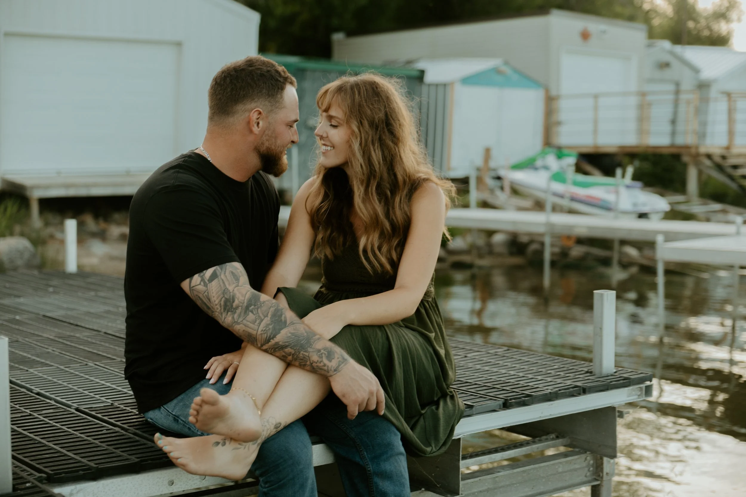 A young girl with red hair and a pink dress holding hands with an adult in a field of plants at sunset.