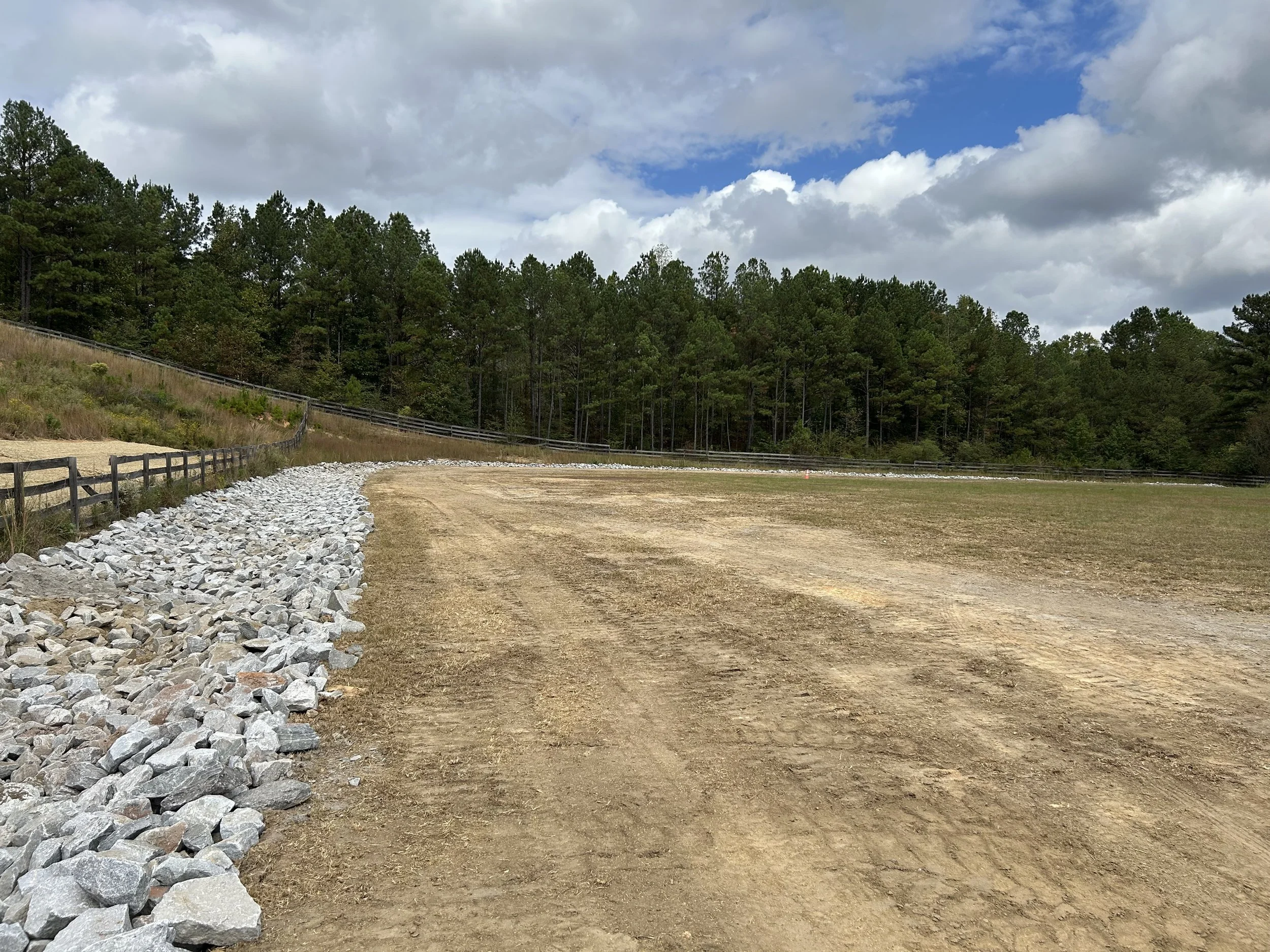 Completed engineered rock-lined channel providing positive drainage around the polo field in Fairburn, Georgia