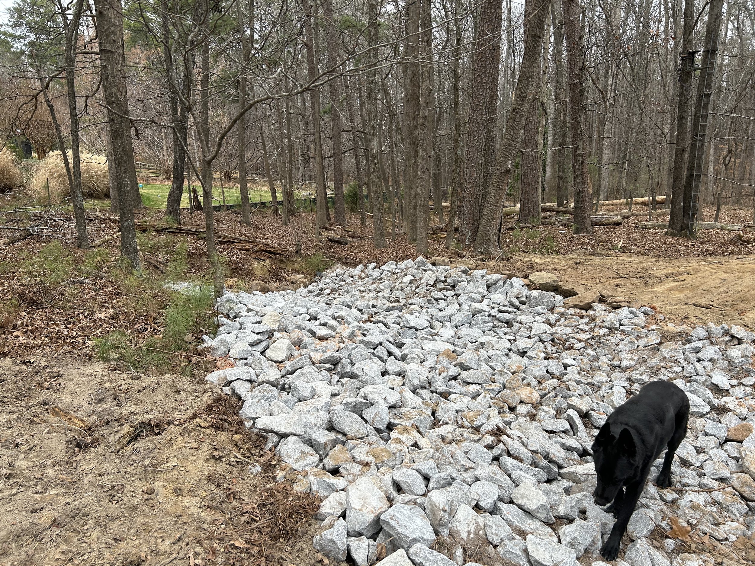 Completed rock-lined emergency spillway designed to safely carry overflow while protecting the pond dam from erosion.
