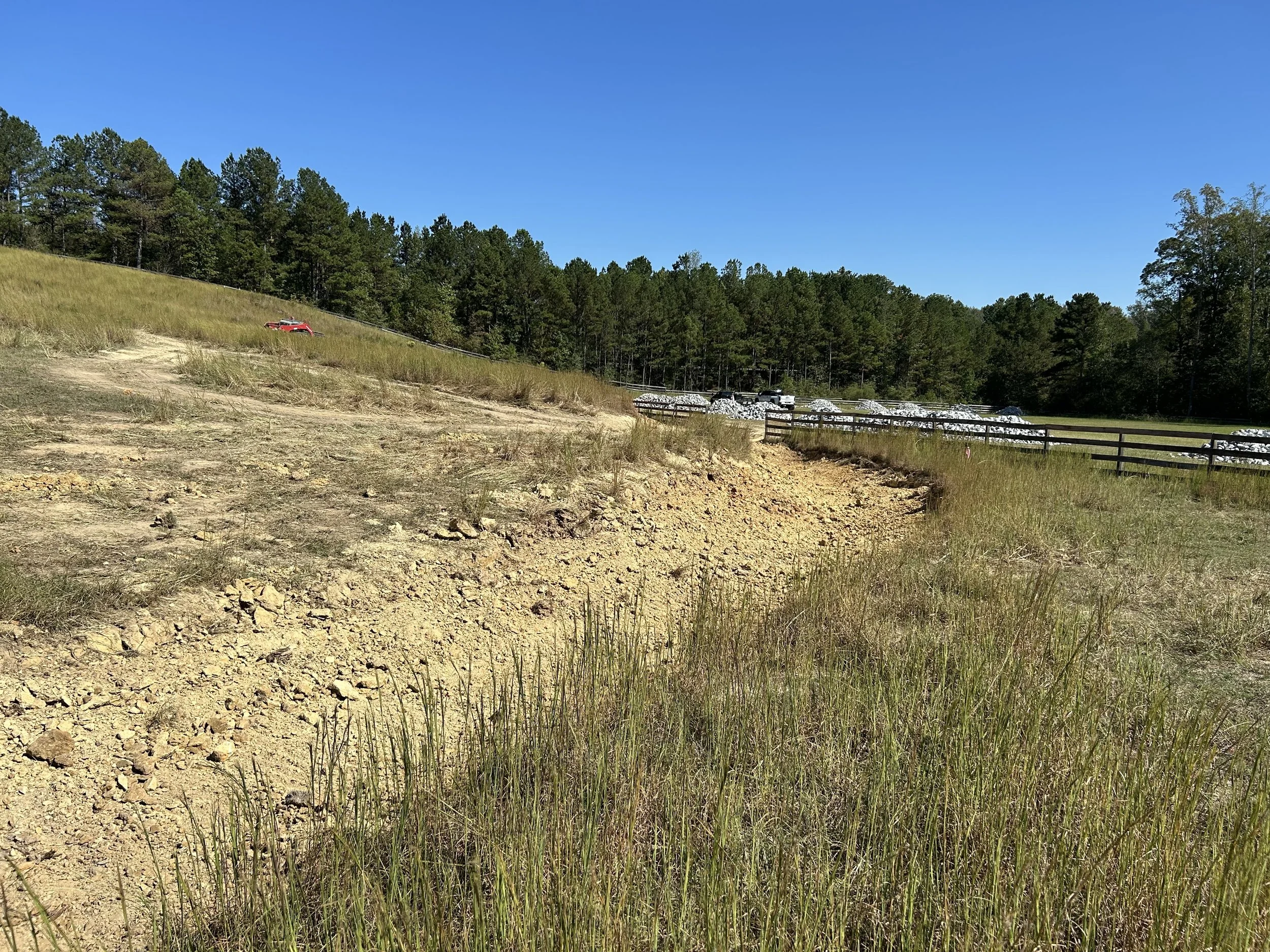 Engineered rock-lined drainage channel in Fairburn, GA. Approximately 700 feet of channel was profiled to engineered grades and lined with geotextile and approximately 540 tons of riprap to establish controlled drainage through the property and a sta