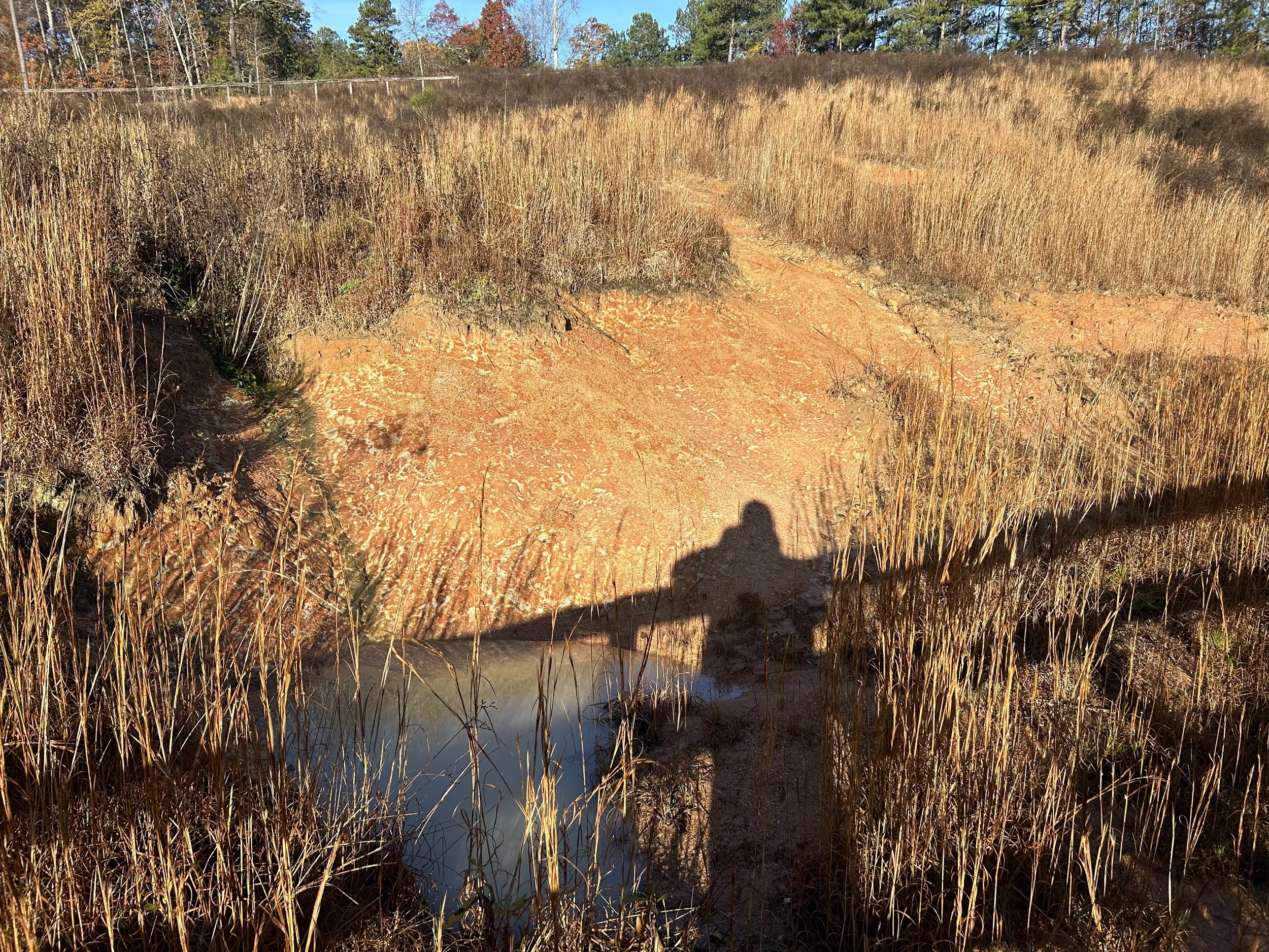 Severely eroded drainage area and washed soil before construction of rock-lined channel in Fairburn