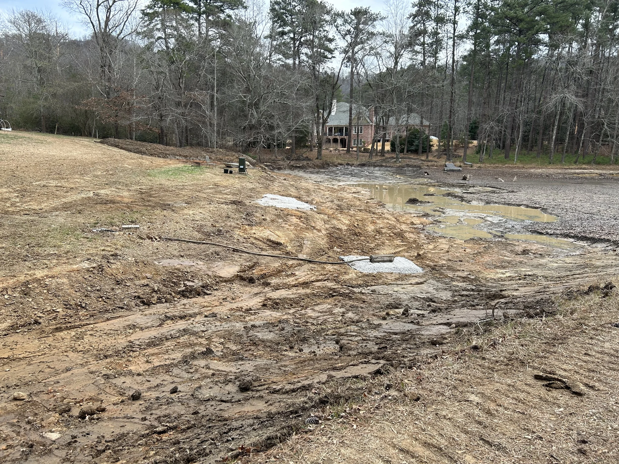 Primary pond head section after dredging, showing the cleaned basin and remaining firm pond bottom beyond the sediment area.