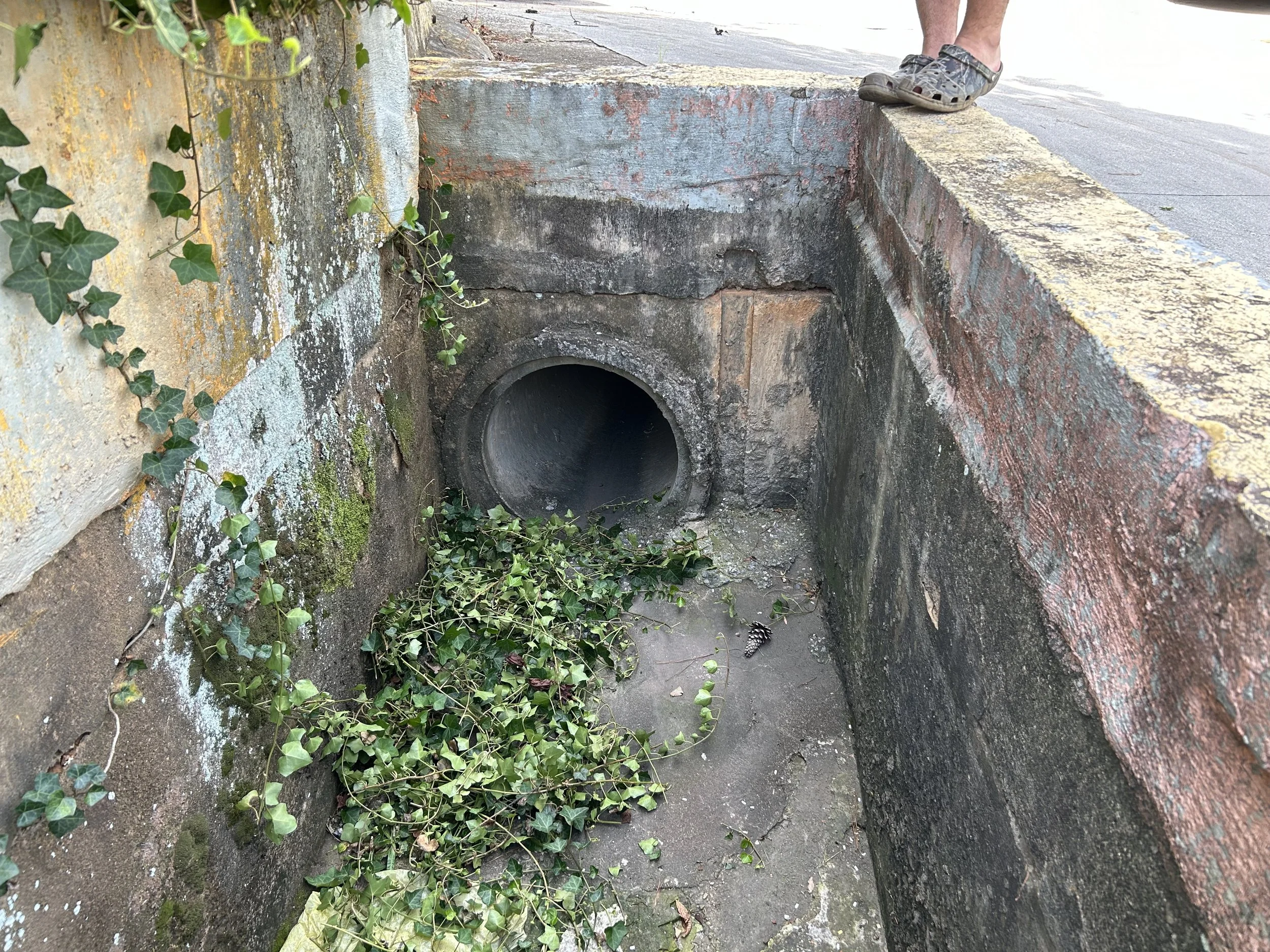 Original open concrete drainage basin and gutter restricting truck maneuvering space at a Mableton industrial facility.