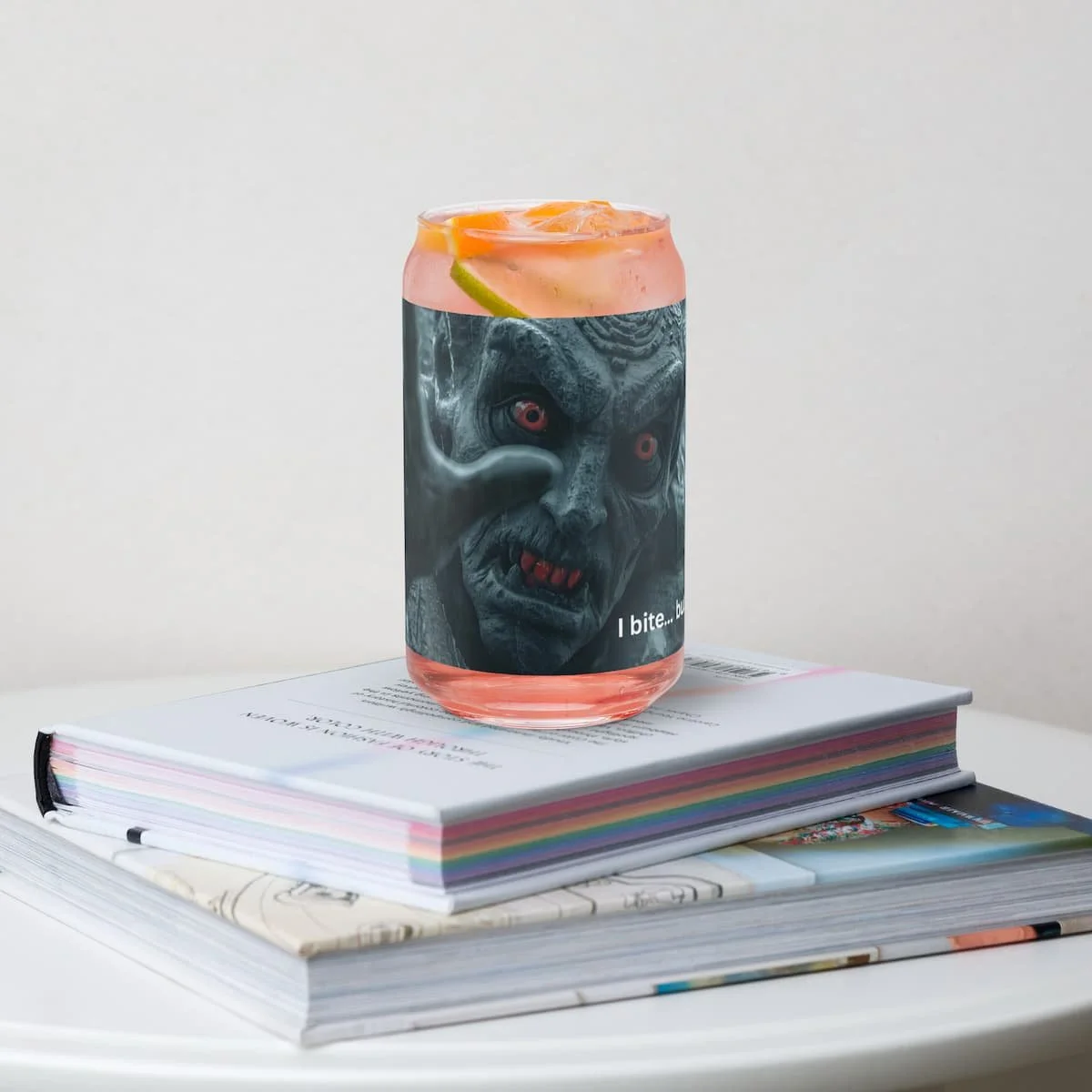 16oz can-shaped glass without lid sitting on a stack of books, perfect for iced drinks or cocktails, styled for a cozy home or office setting