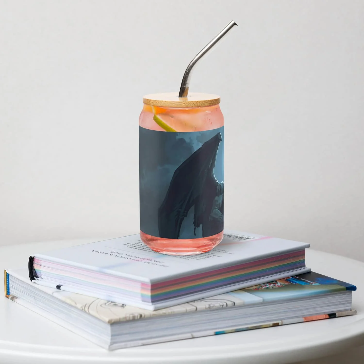 Right view of 16 oz can-shaped glass with lid and straw on a book on a table