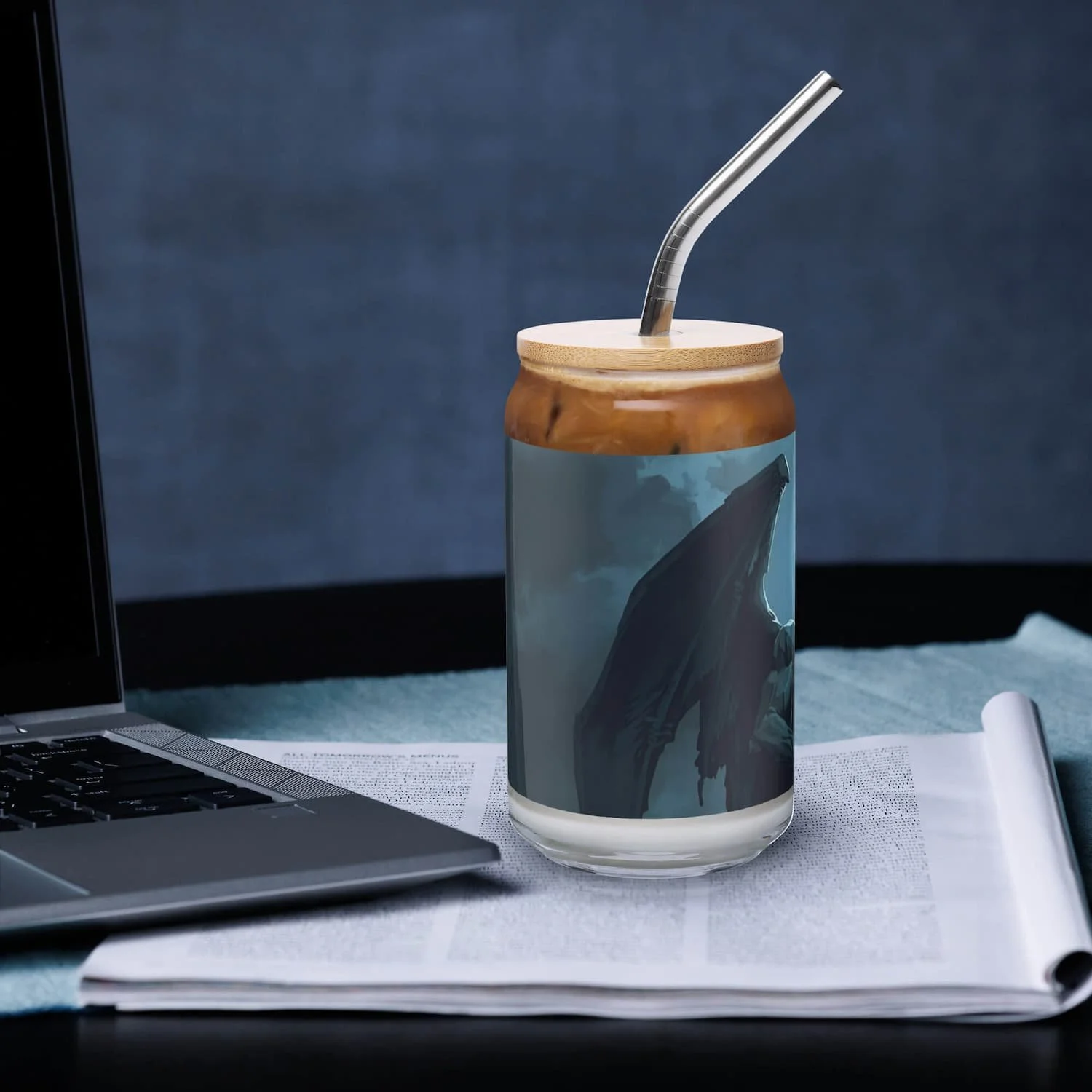 16 oz can-shaped glass with lid and straw sitting on a table next to a laptop, right side view, clear reusable drinkware cup