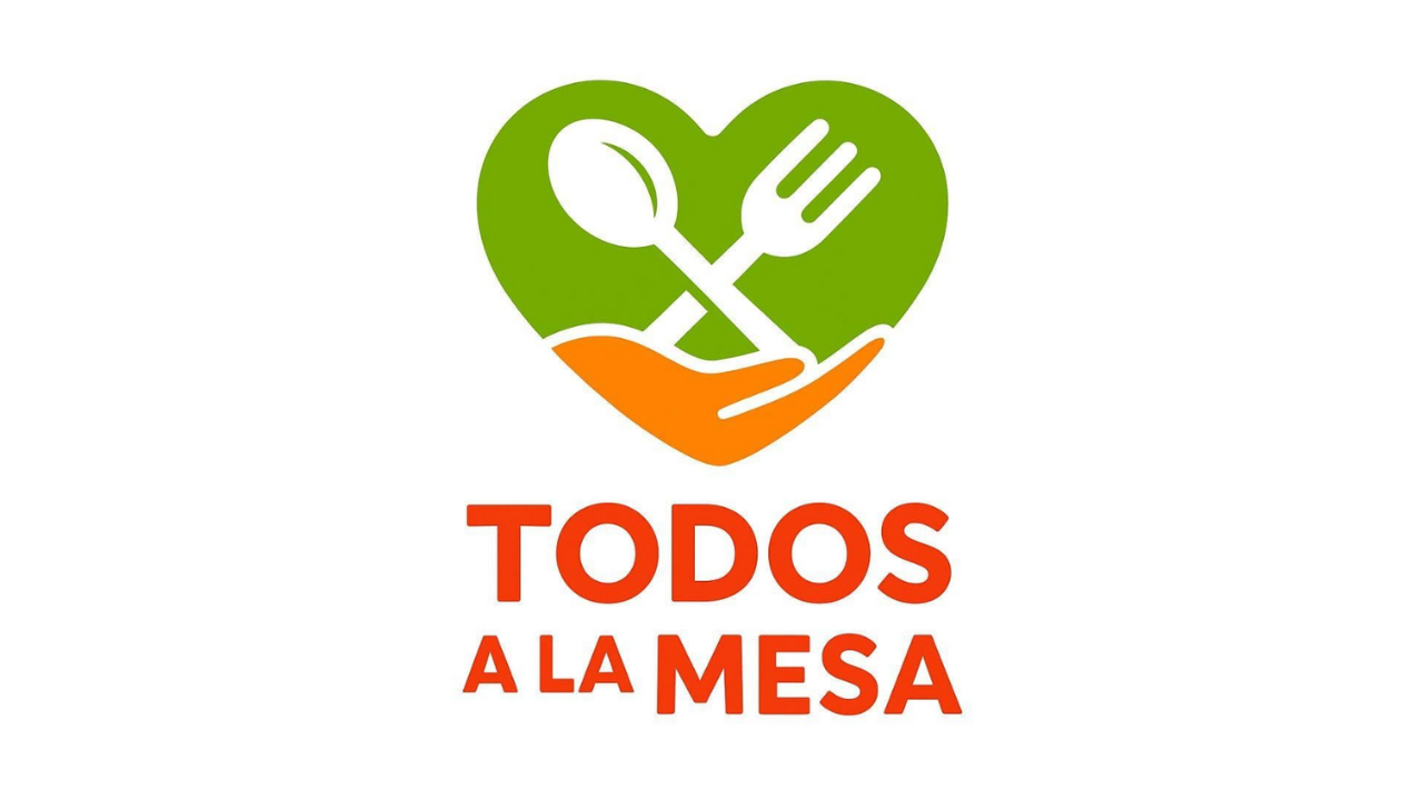 Logo con corazón verde y naranja, con una cuchara y un tenedor cruzados en el centro, y texto en rojo que dice "Todos a la mesa".
