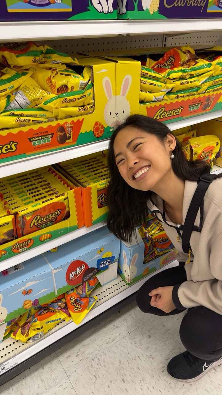Smiling person posing beside shelves of Reese's Easter candy.