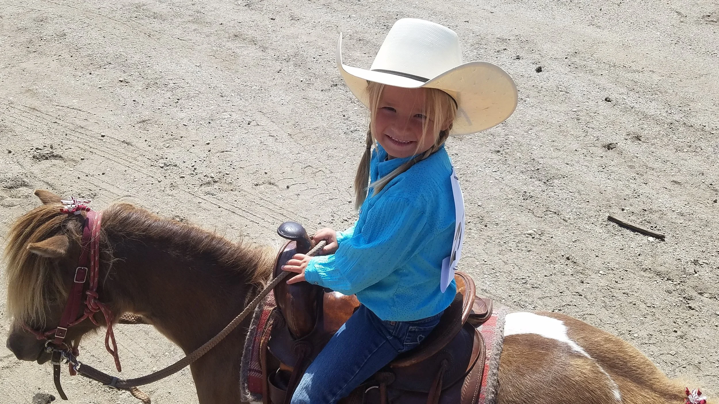 A young girl in a cowboy hat riding a small pony.