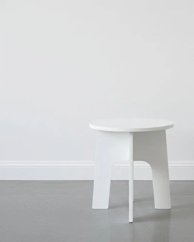 Lightweight folding chair painted white in a studio with white wall and polished concrete floor