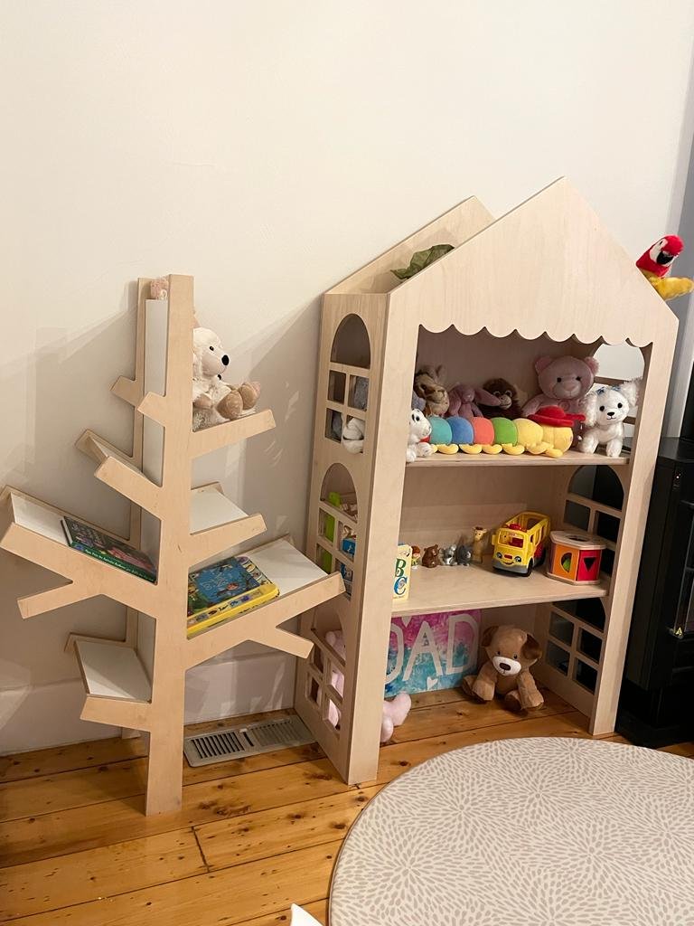 Freestanding dollhouse display shelf made from raw birch plywood with window cut-outs and scalloped trim. Features 3 shelves and pitched roof design. Ideal for events, kids’ rooms, or markets.
