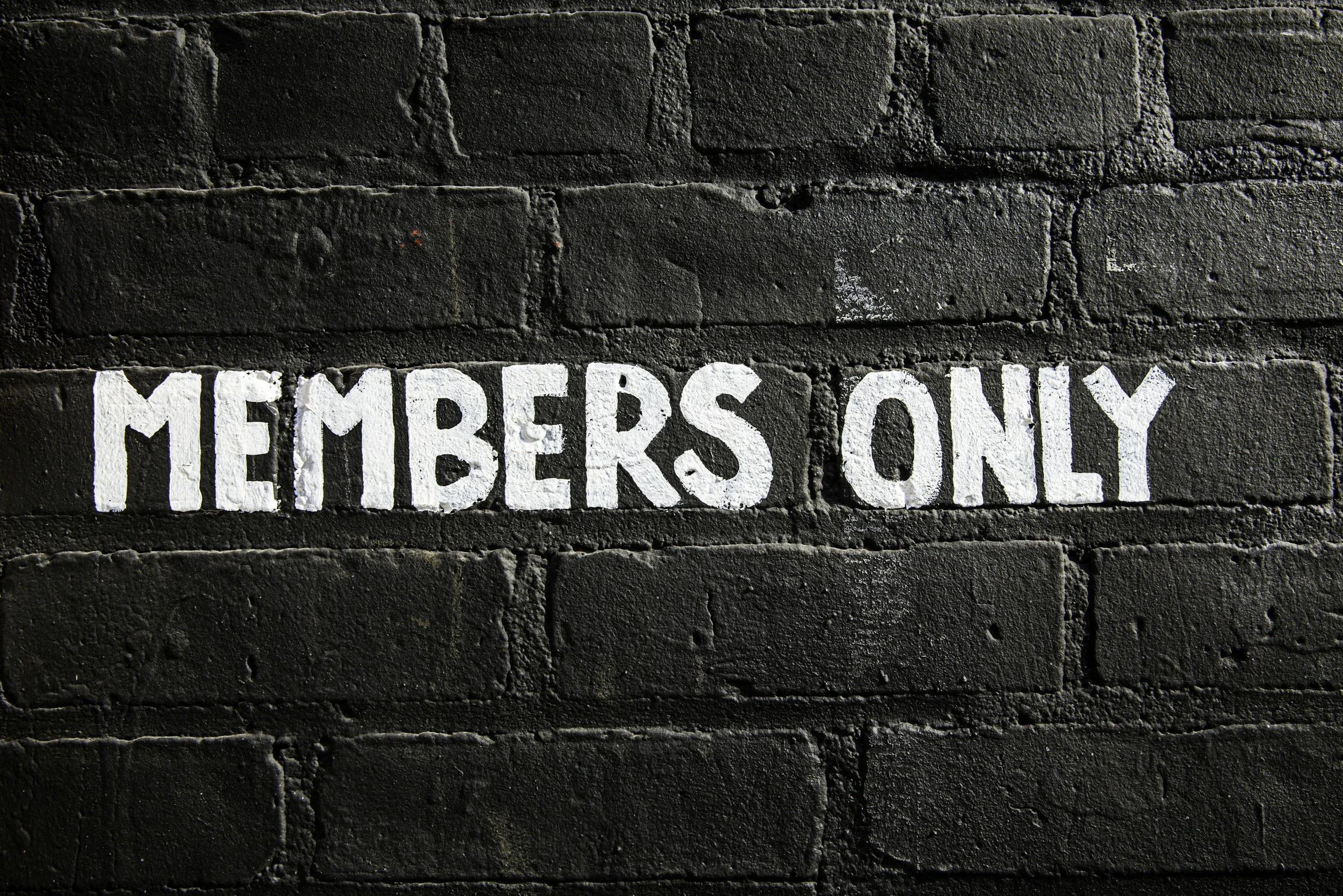 Black brick wall with white painted words 'MEMBERS ONLY' on it.