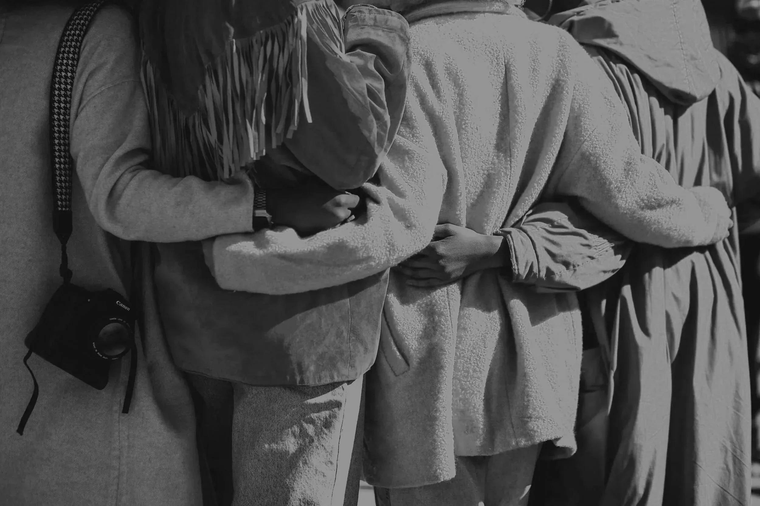 People lying on a bed or couch, covered with blankets, with their heads resting on pillows.