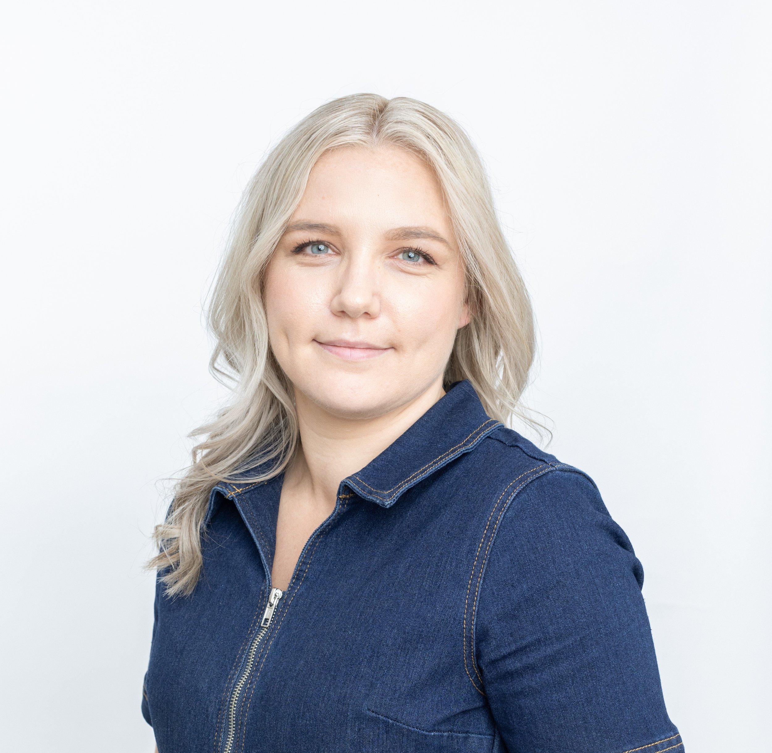 Portrait of a woman with blonde hair wearing a denim jacket against a plain white background.