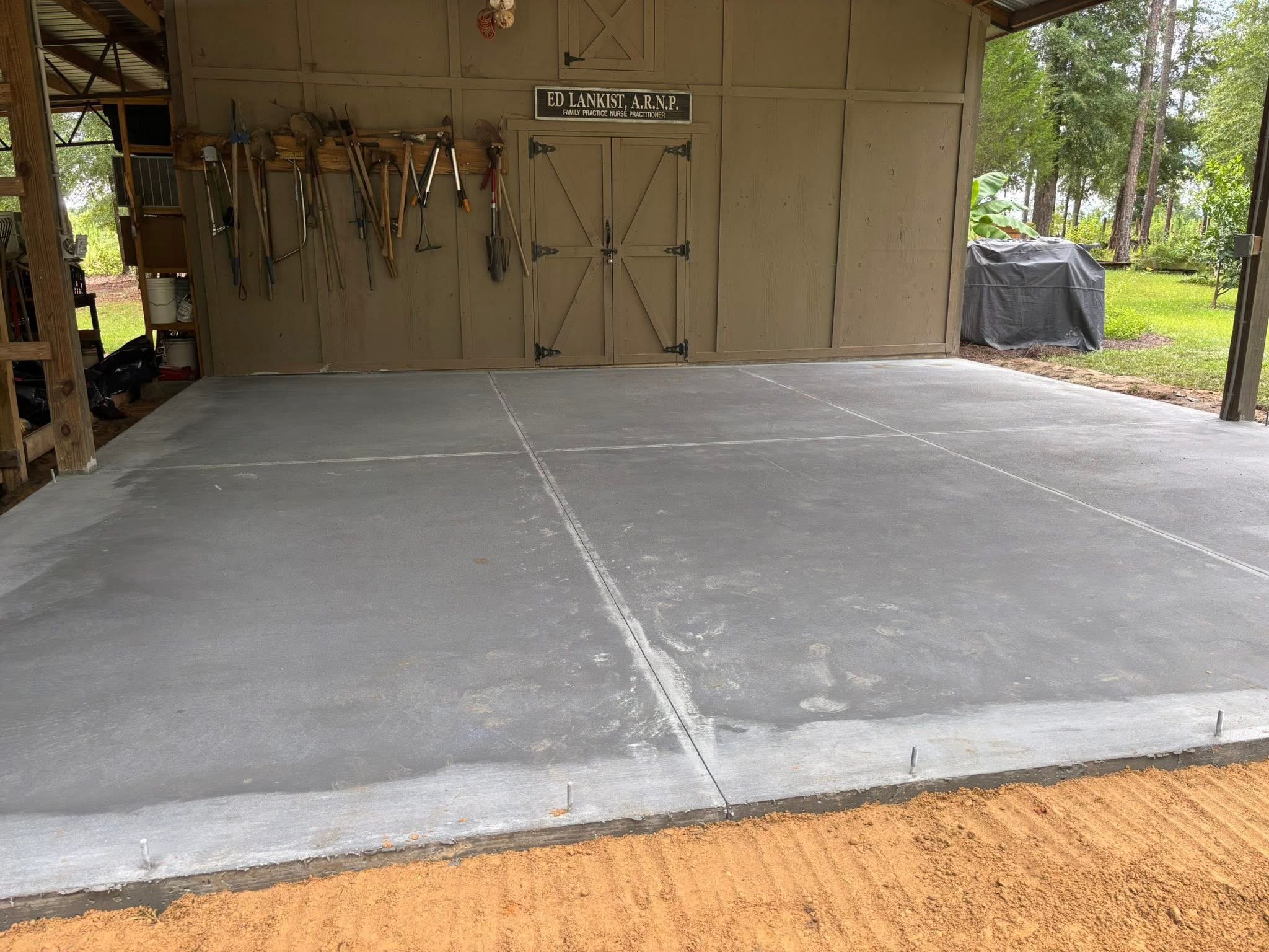 Residential concrete parking pad under existing pole barn.
