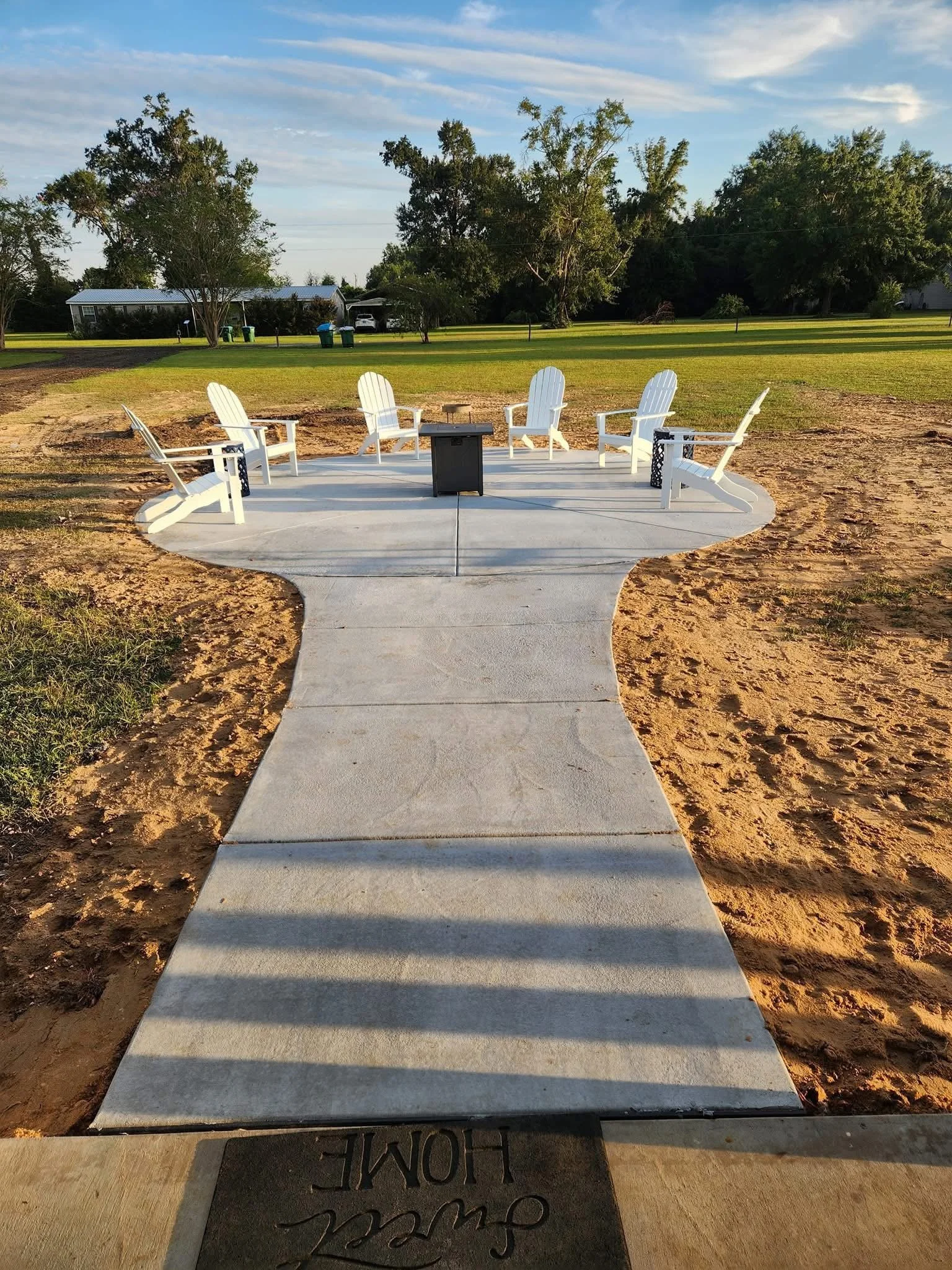 Residential front yard walkway with fire pit and seating area.
