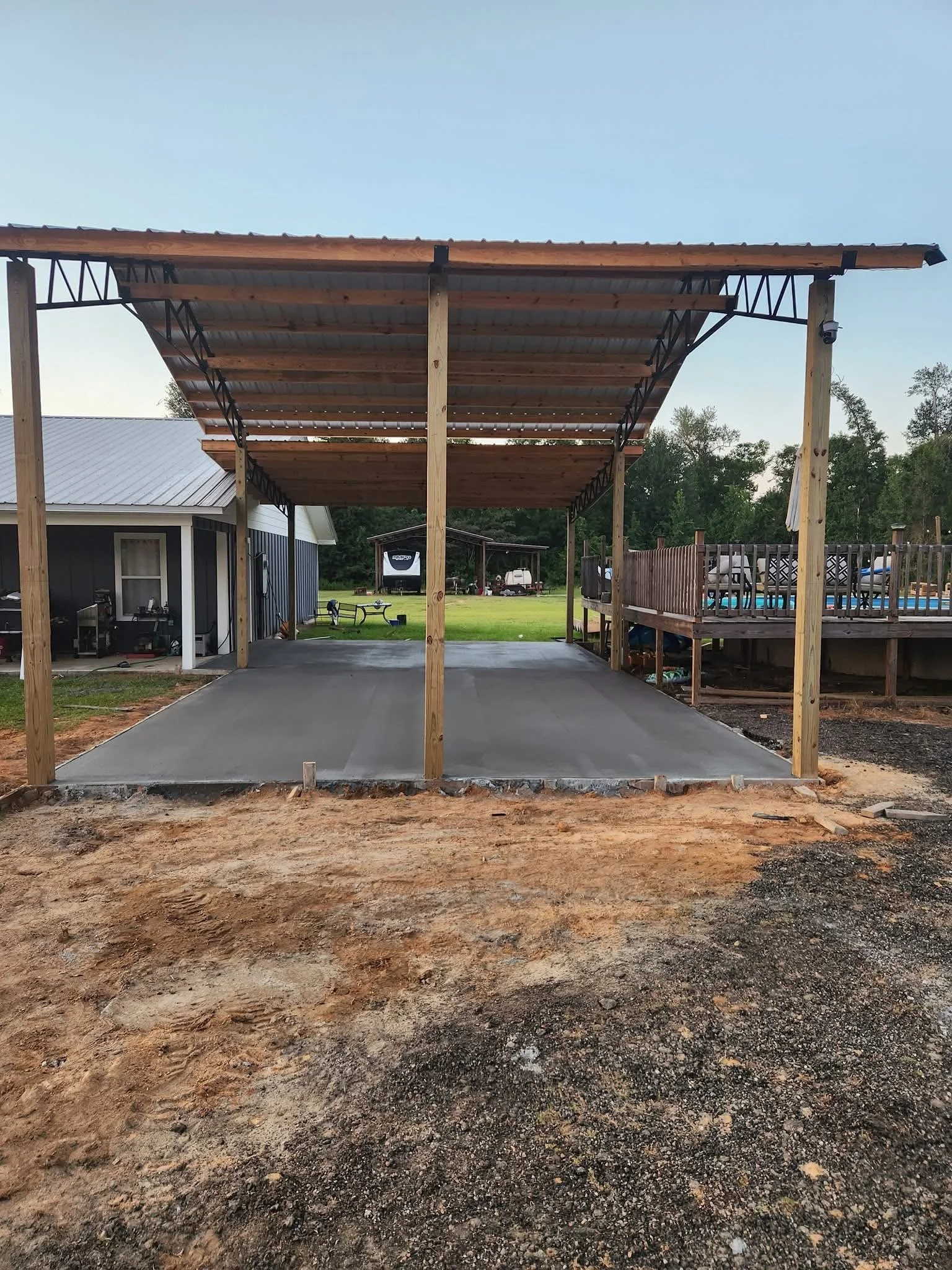 Concrete slab and pole barn to connect pool and the house to allow covered parking area for residential owner.