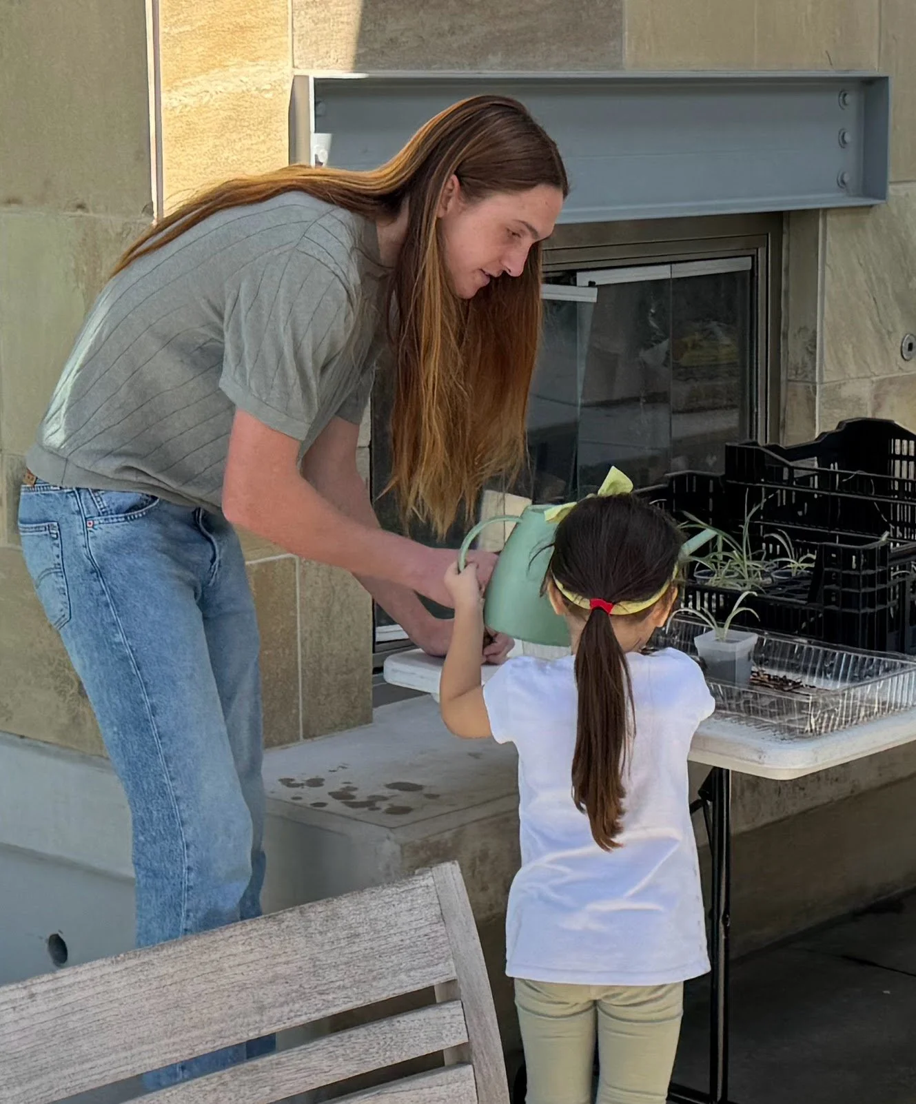 Planting Smiles' founder helping a young girl water her plant.