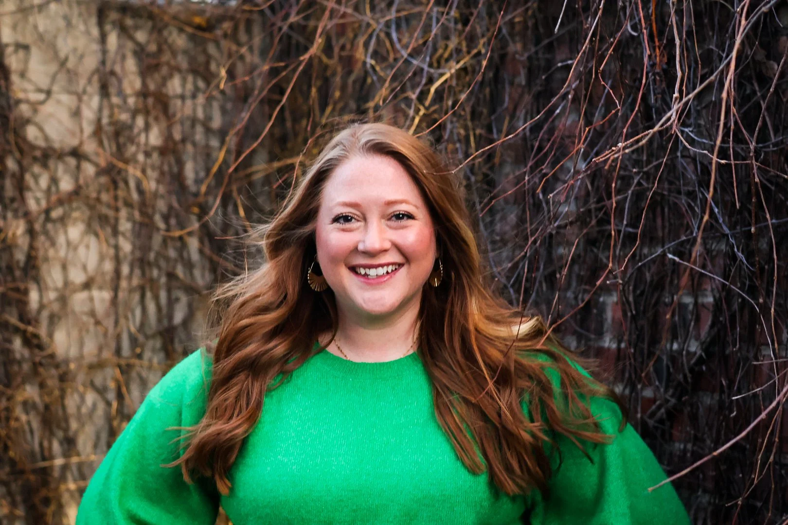 Chelsea Schrunk Crivello in a green sweater with a background of tangled vines.