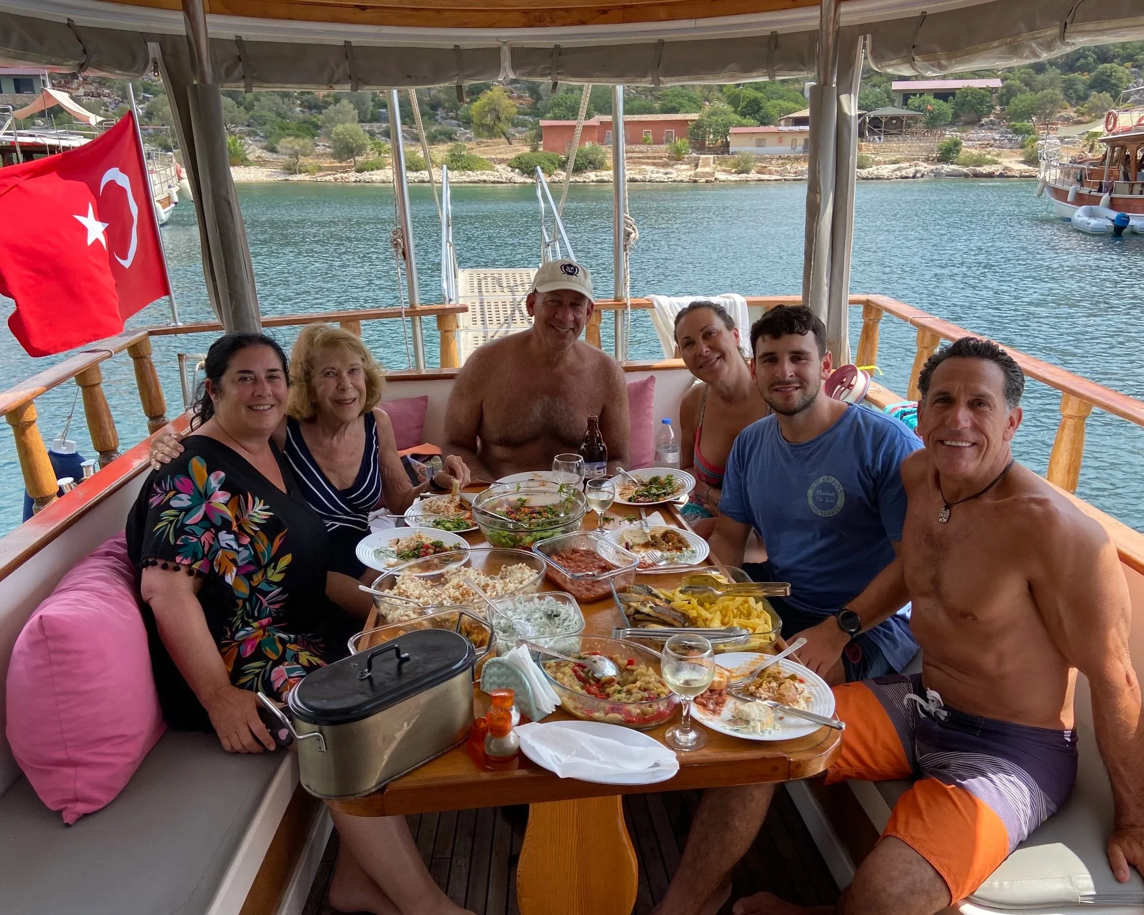 Family enjoying a meal on a Turkish boat, clear torquiest water, and having an amazing time sailing on the Turkish riviera.
