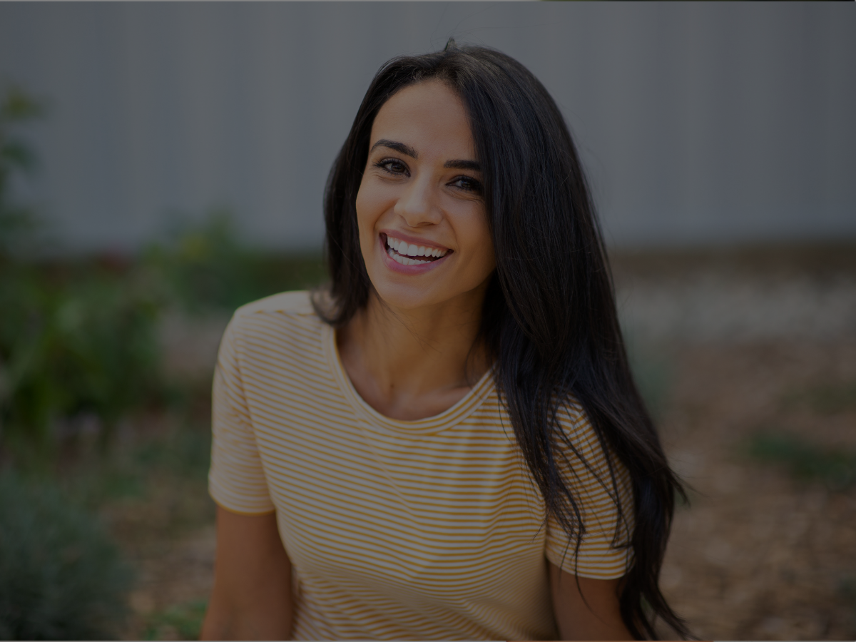 Smiling female patient outdoors representing cosmetic dentistry results and confident smile at Dental Excellence