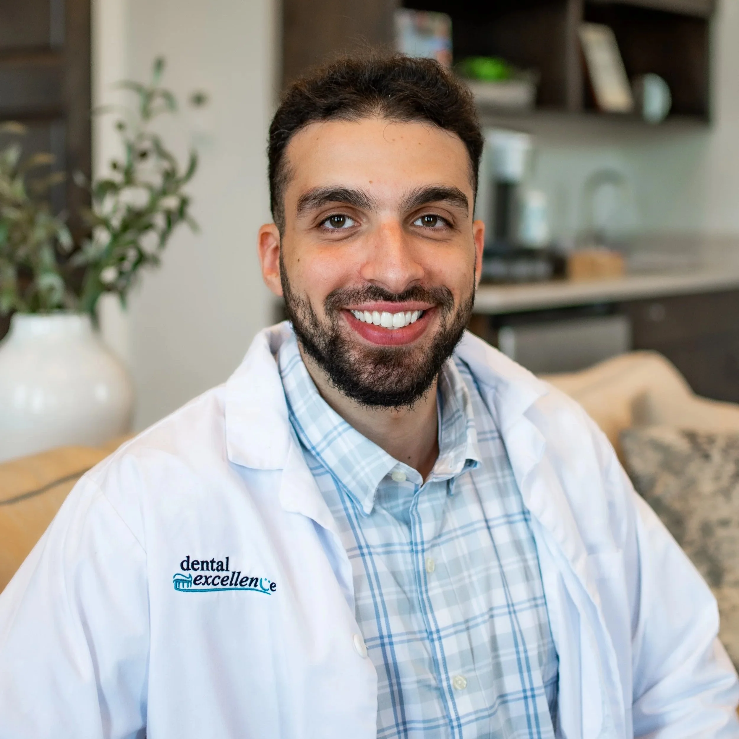 Dr. Adam Jazaerly smiles while wearing a Dental Excellence lab coat in the office, providing comprehensive family and general dentistry in Northwest Ohio.