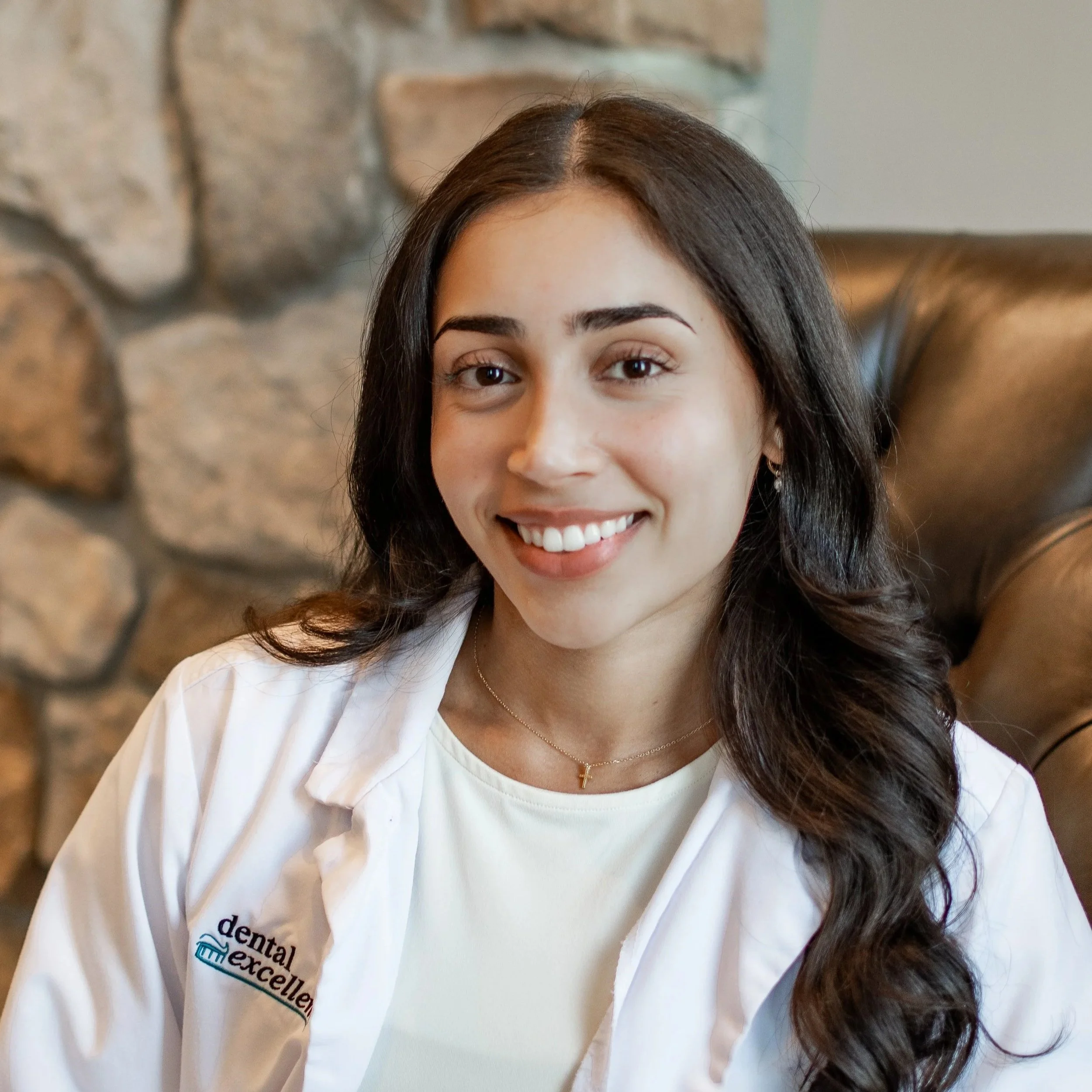 Dr. Dina Desai smiles while wearing a Dental Excellence lab coat in the office, providing comprehensive family and general dentistry for patients in Northwest Ohio.