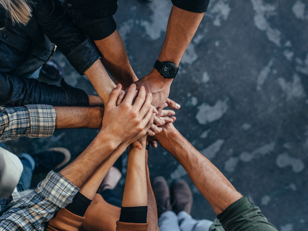 Dental team members with hands stacked together representing teamwork, collaboration, and patient focused care at Dental Excellence
