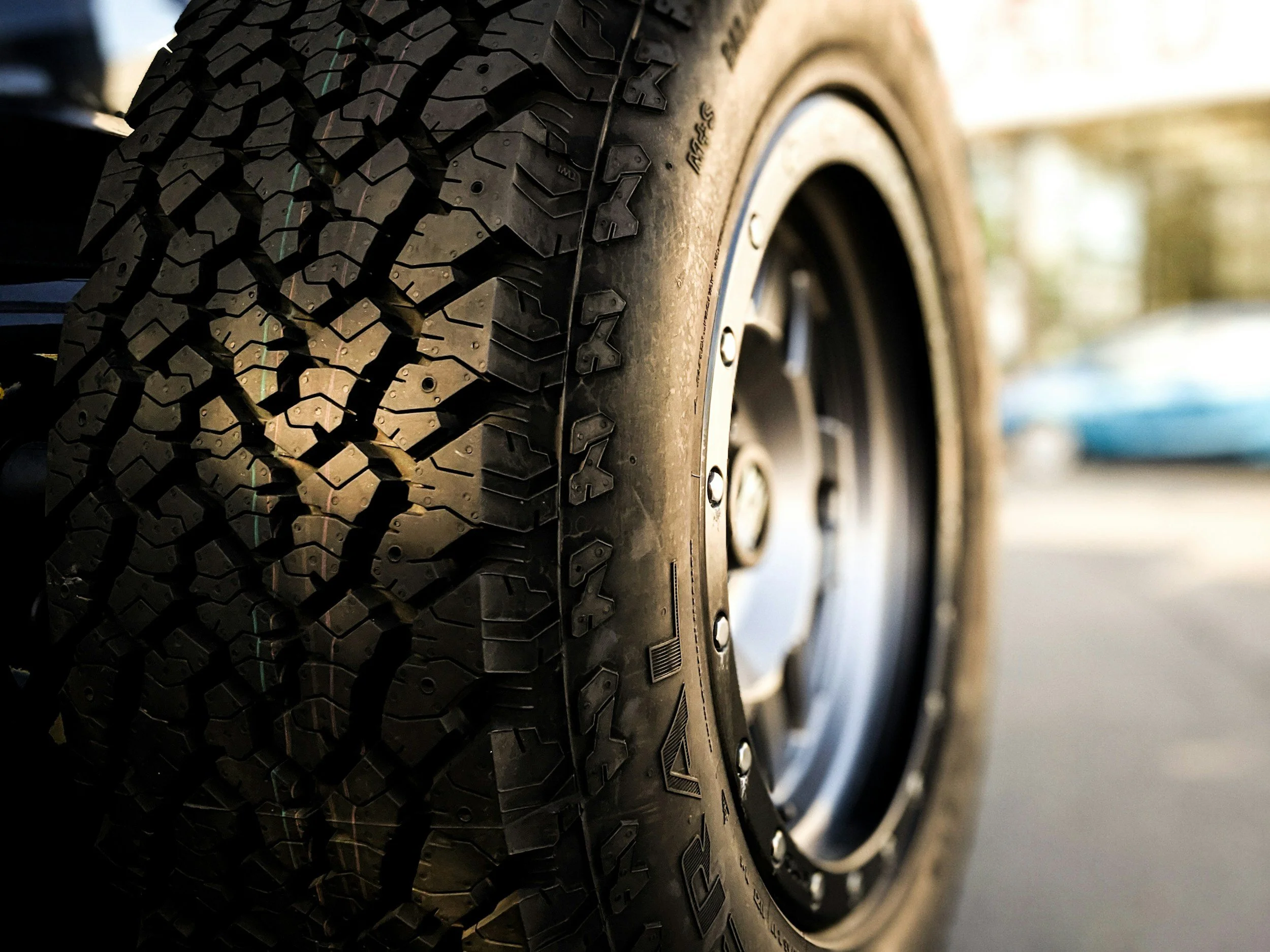 Close-up of a car tire with detailed tread and black rim, on a paved road