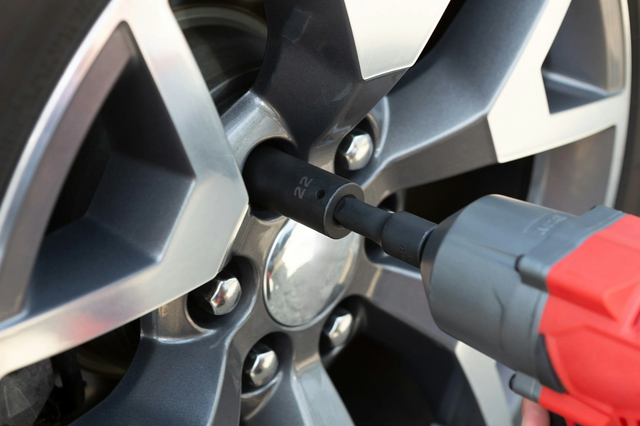 Close-up of a car wheel with a tool being used to remove or tighten lug nuts.
