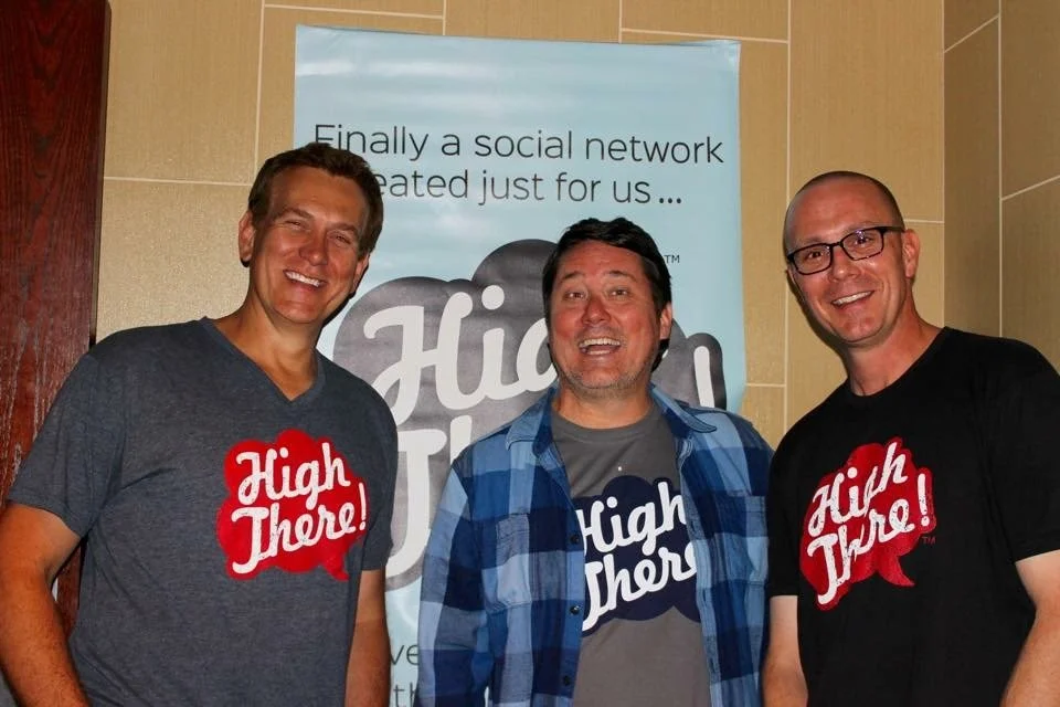 The three High There co-founders in High There tees in front of the brand banner