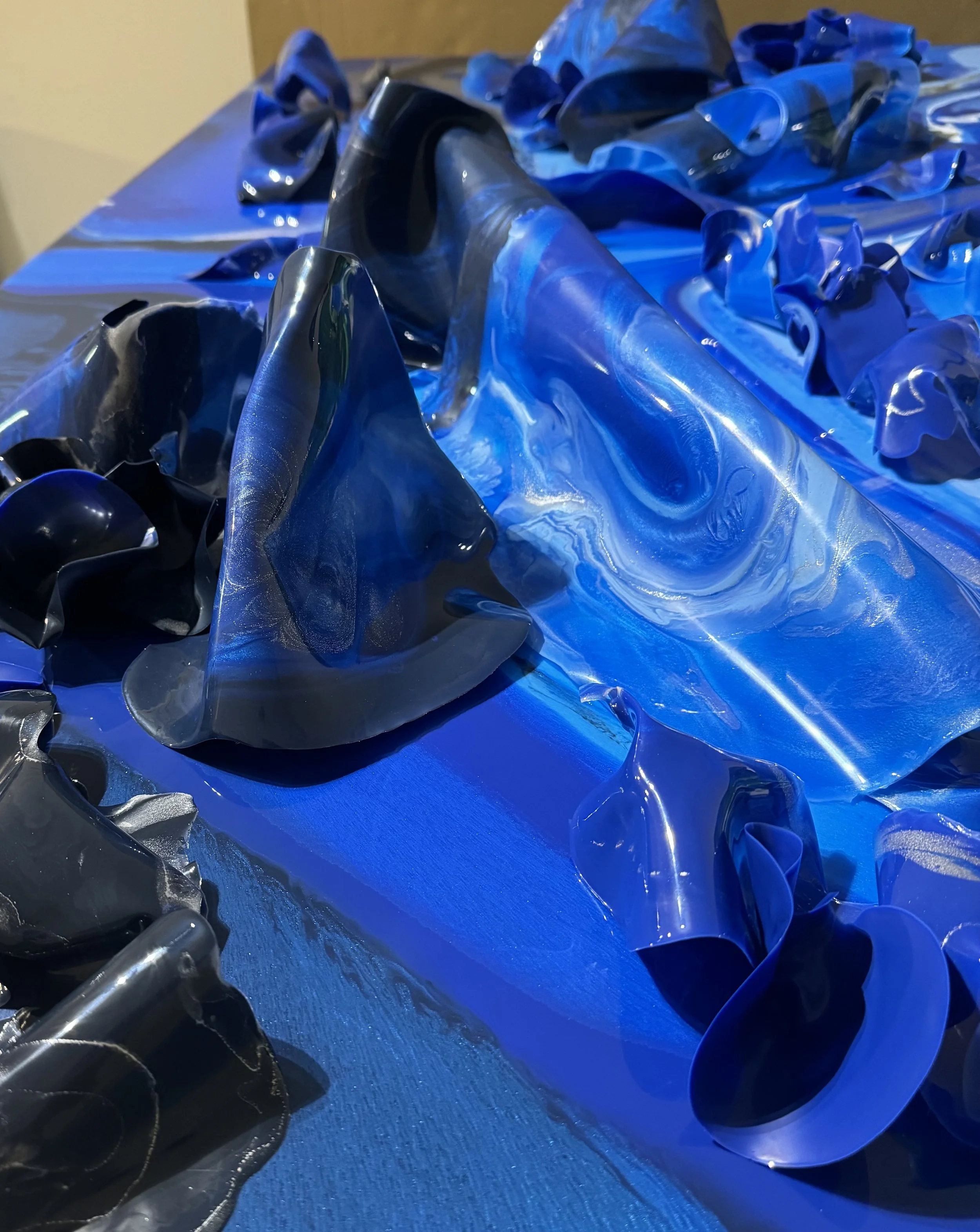 Close-up of blue and black crumpled and folded plastic or rubber material on a blue surface.