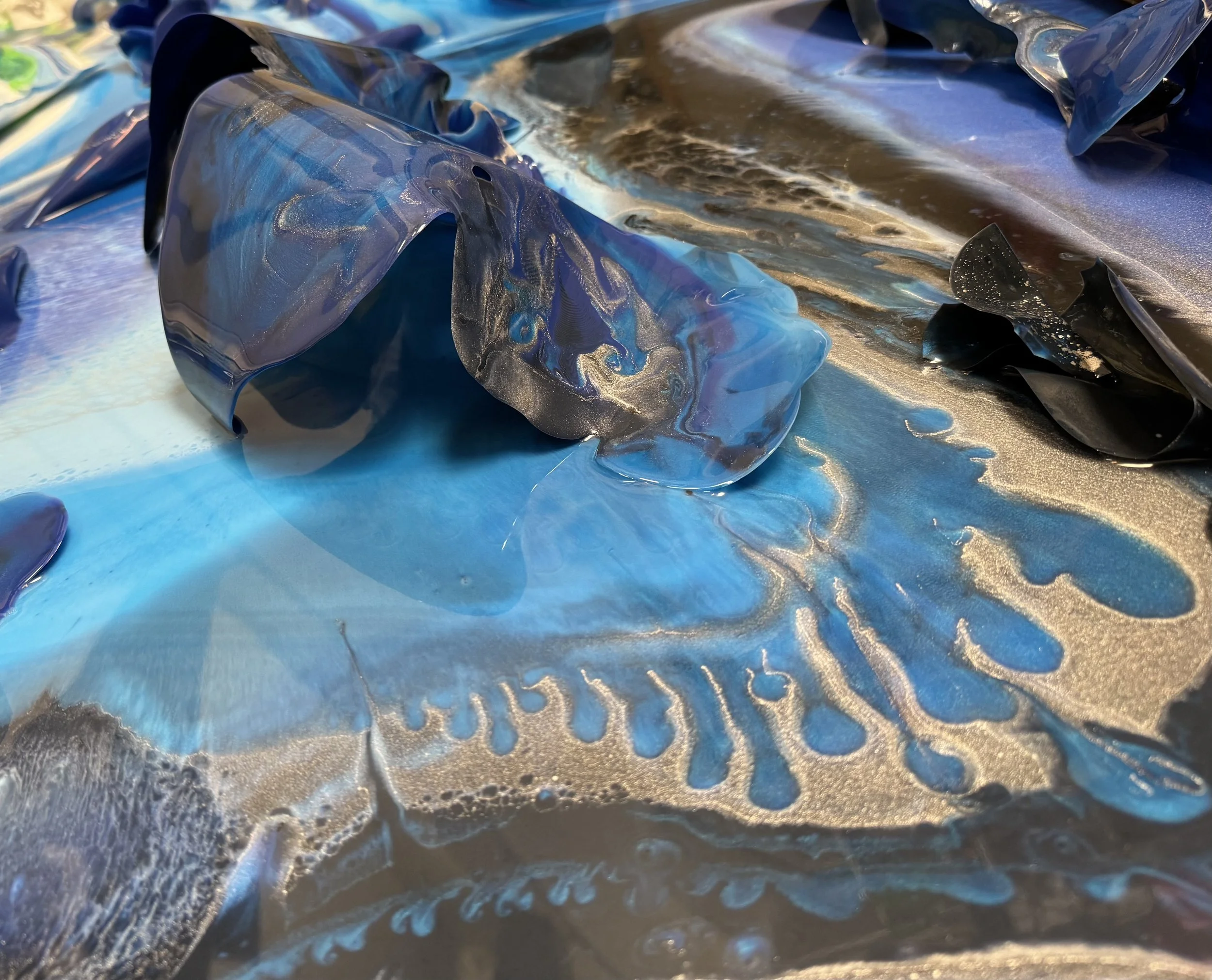 Close-up of crumpled metallic and blue plastic sheets with swirling patterns and reflective surface.