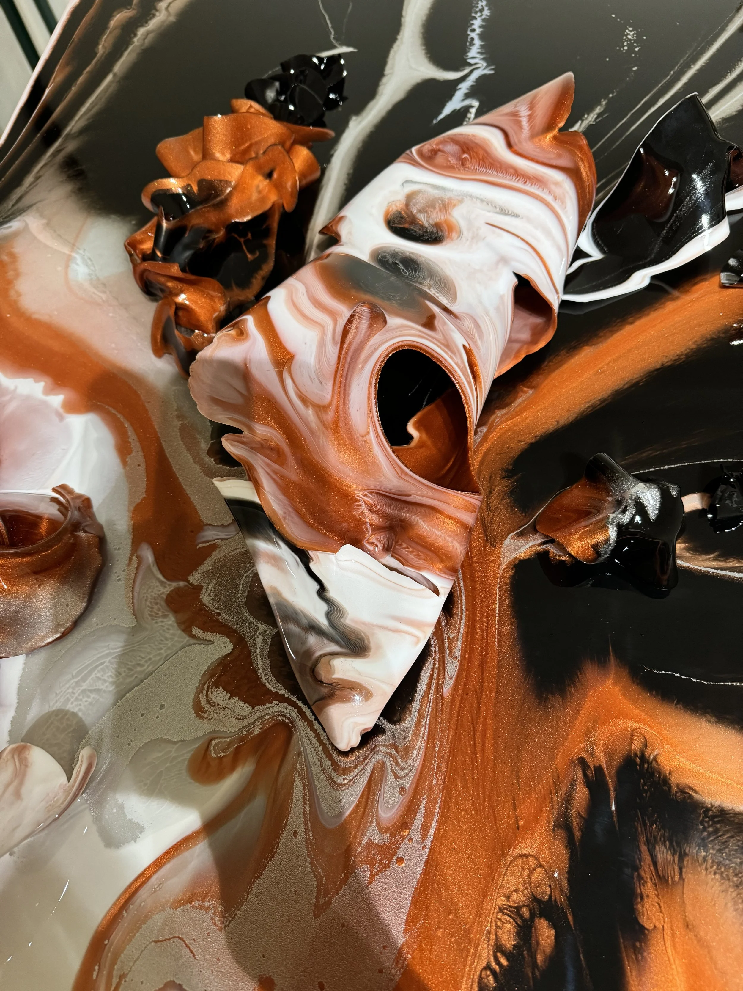 Abstract swirling pattern with black, white, orange, and brown colors, resembling marbled or fluid art.