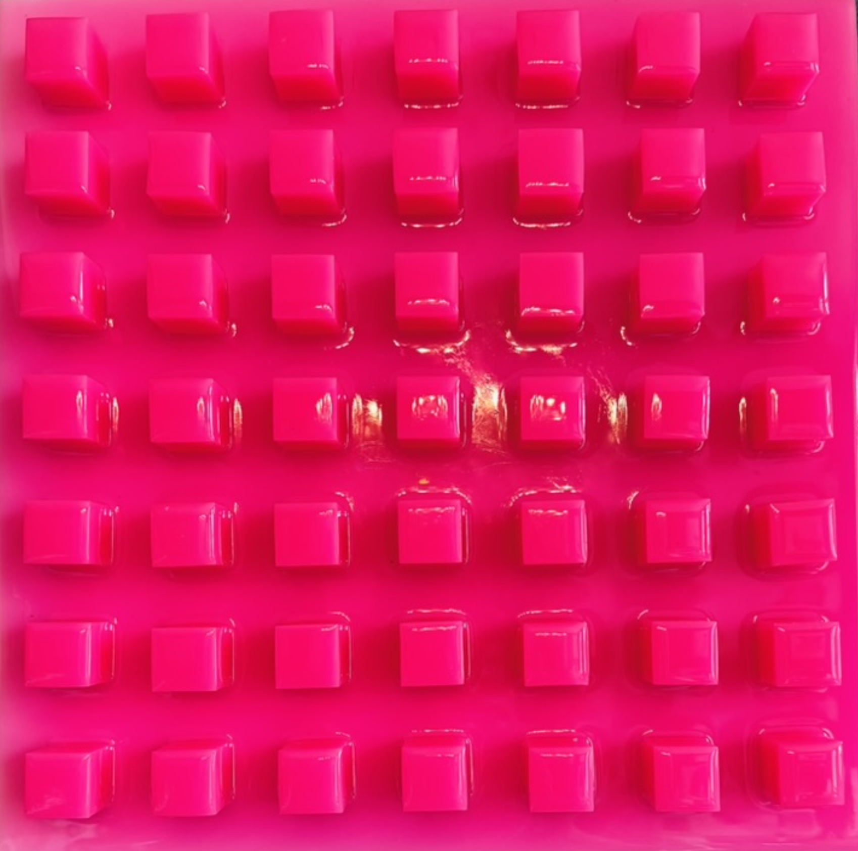 Pink plastic tray with multiple empty square indentations.