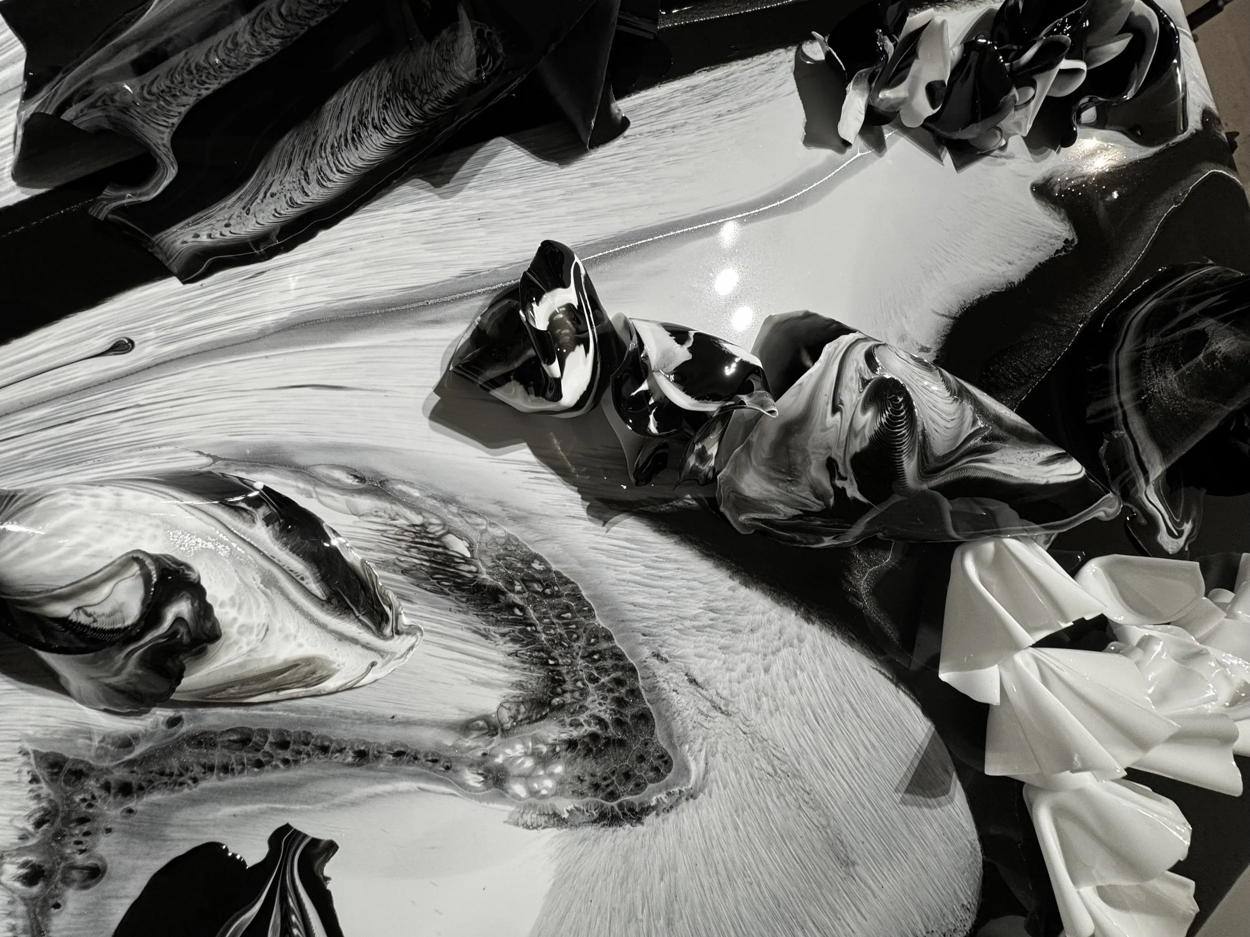 Abstract black, white, and gray swirled paint with textured and glossy surfaces.