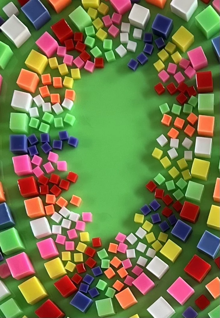 Colorful square and rectangular tiles arranged in a circle on a green background.