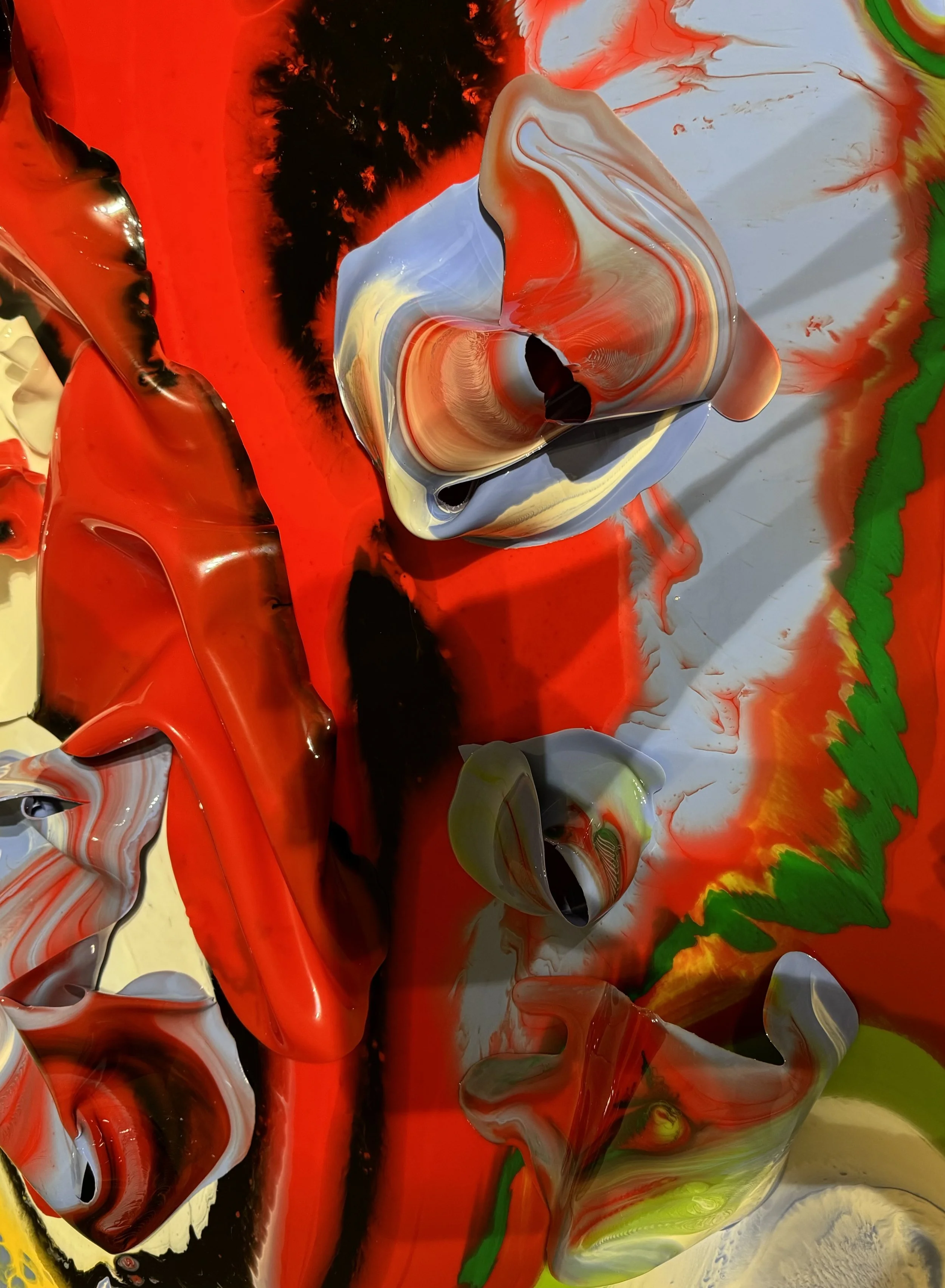 Abstract swirl of red, black, gray, yellow, and green paint in a fluid pattern.