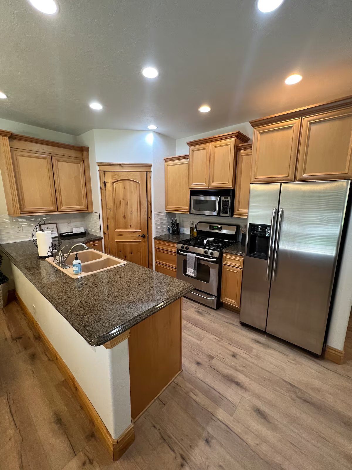 Modern kitchen with light wood cabinets, granite countertops, stainless steel appliances, and recessed lighting.