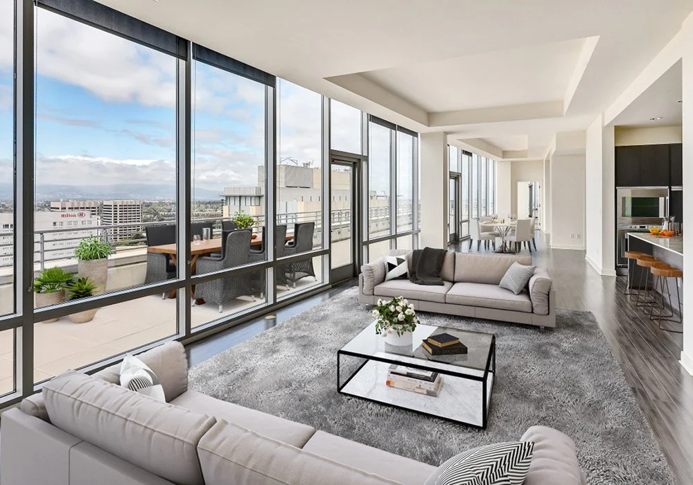 Modern living room with floor-to-ceiling windows, a balcony with outdoor seating, and city views.