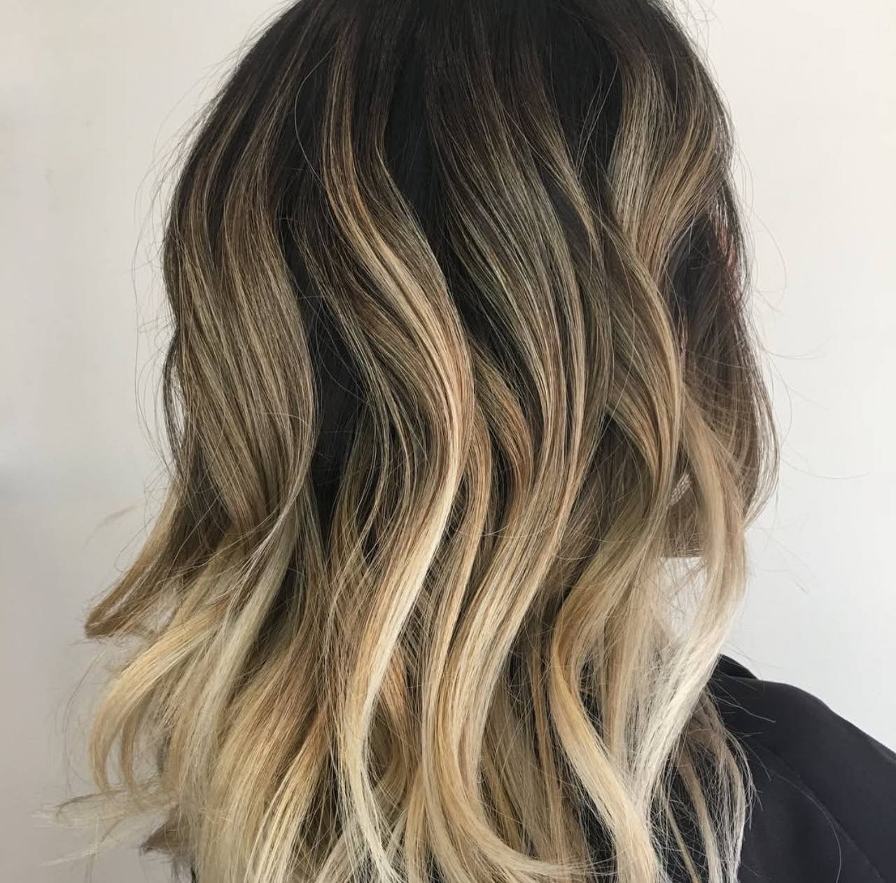 Close-up of wavy ombre hair with dark roots and light blonde ends