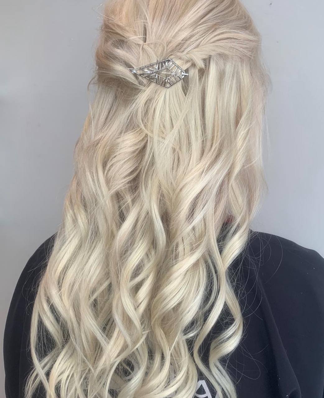 Back view of blonde hair styled in loose curls with a decorative silver hair clip.