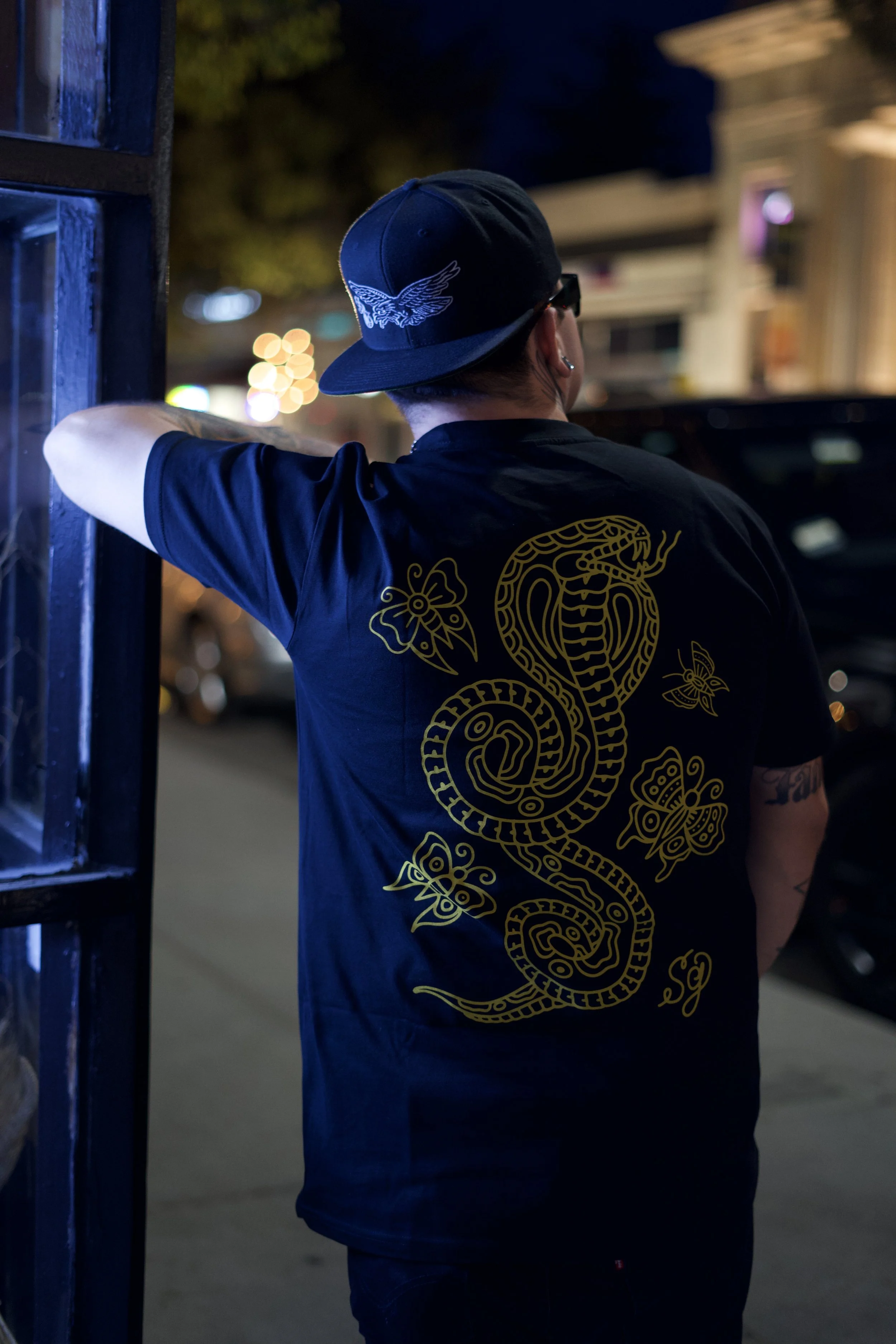 a young man/model leaning wear a designer shirt and hat