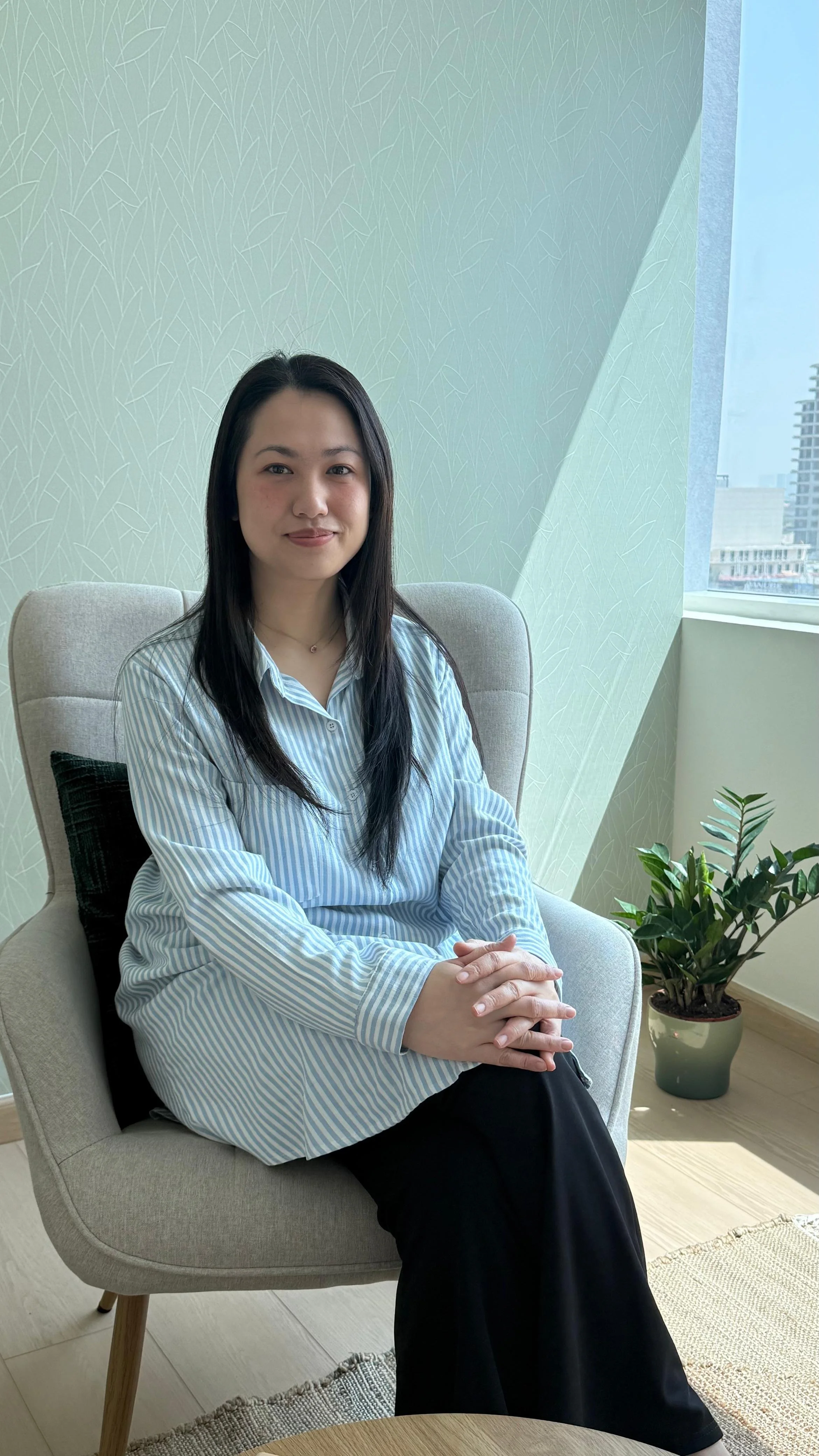 Ailien Sy, Peninsula's psychologist, sitting in a chair facing the photo.
