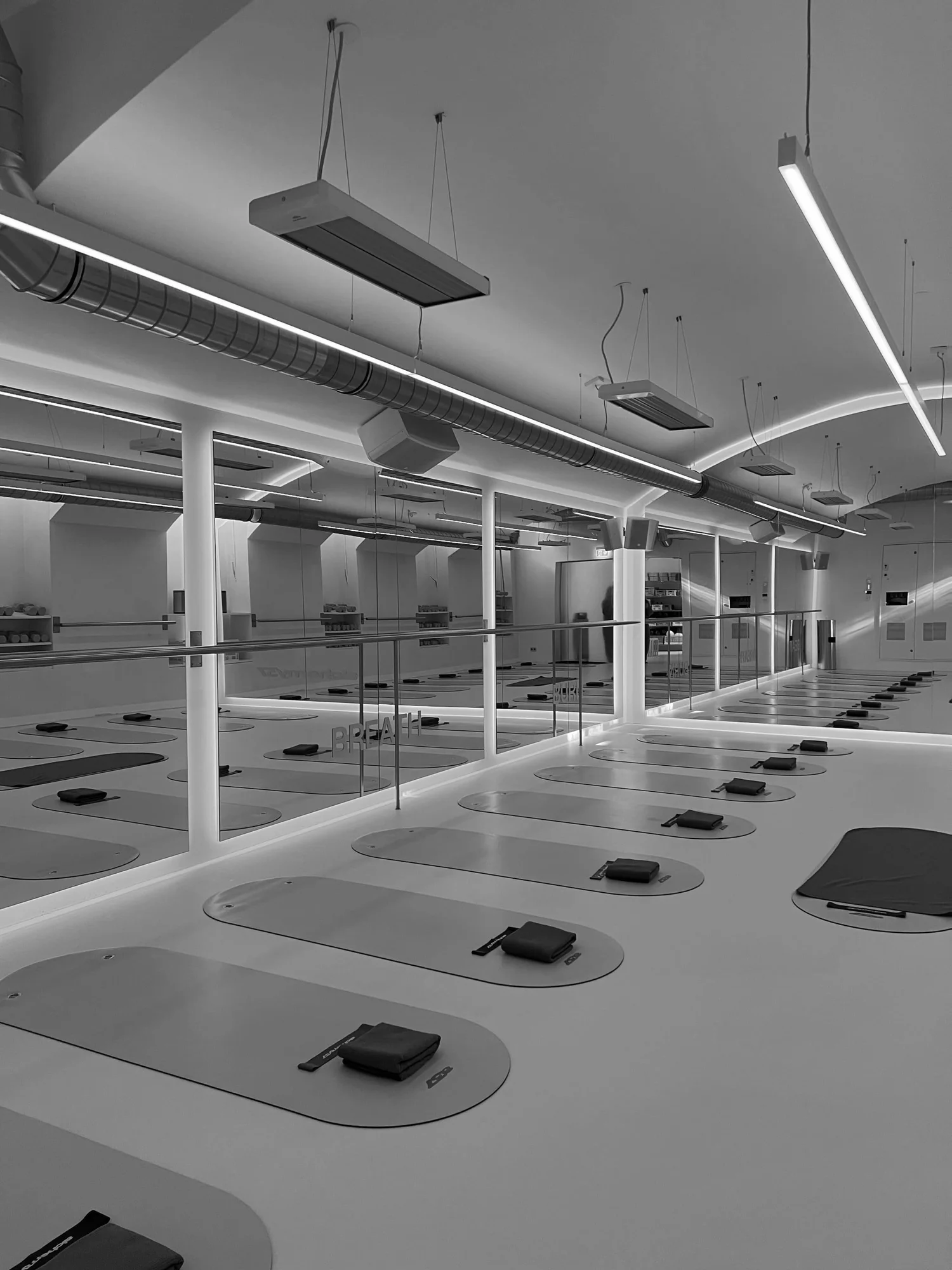 The studio floor at low light, mats beneath linear ceiling lights