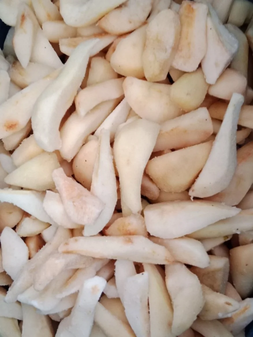 Chopped frozen pear slices inside a blue plastic container.